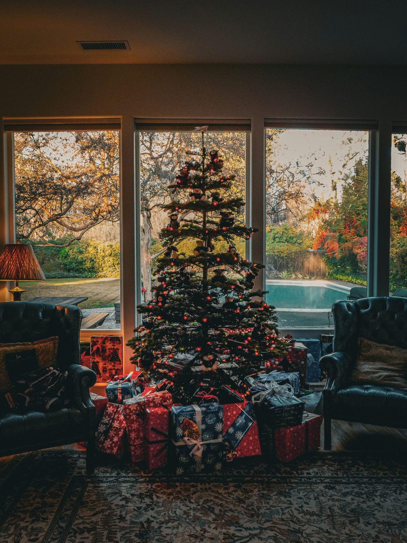 A decorated Christmas tree with wrapped gifts in a living room at golden hour
