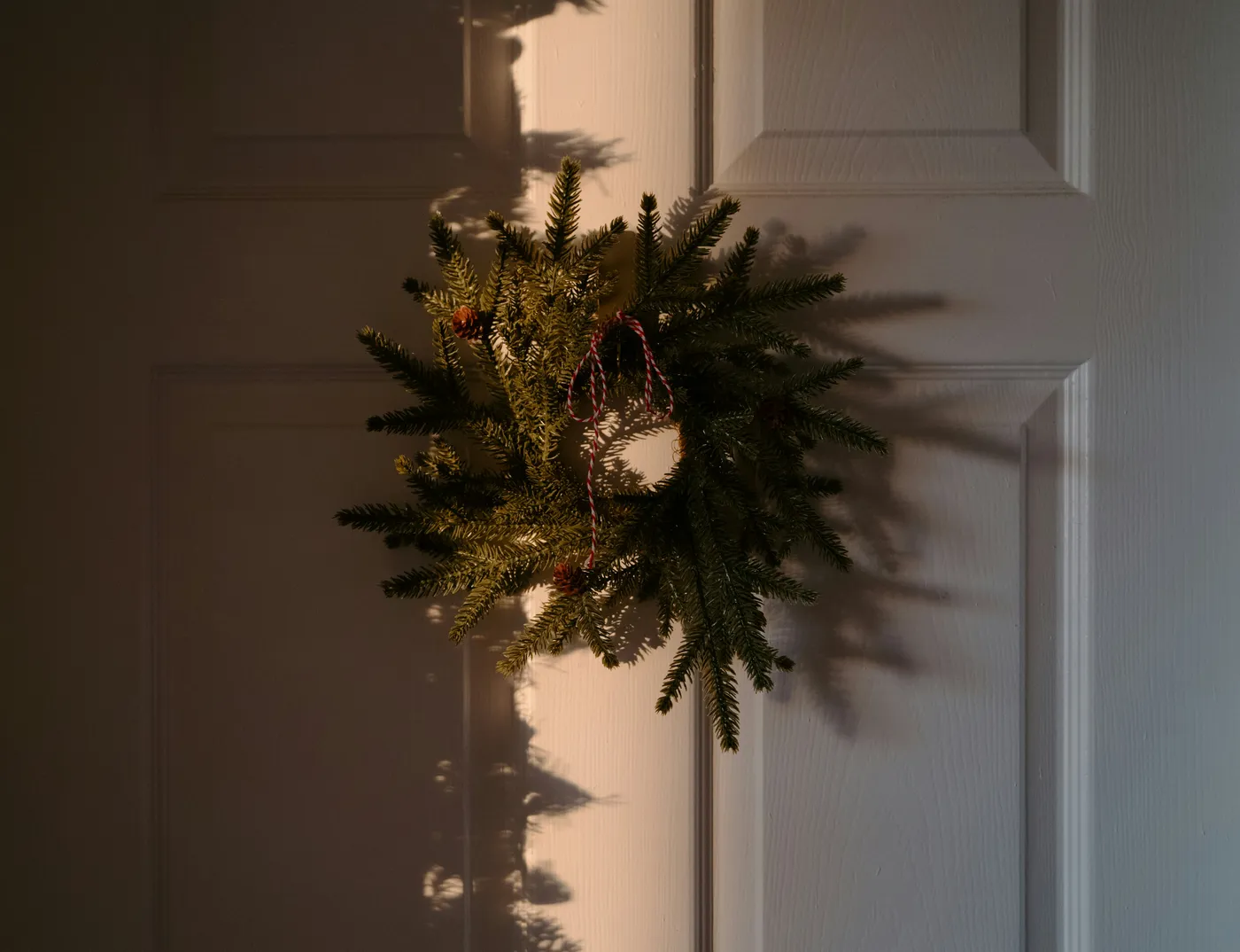 A festive wreath hangs on a white door