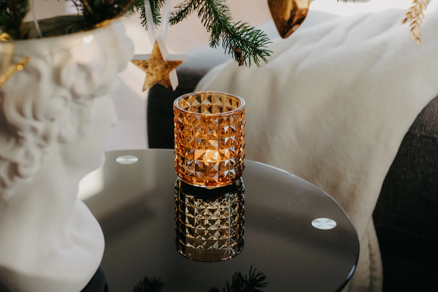 A geometric candle holder on a reflective coffee table with festive decor, evoking warmth and elegance.