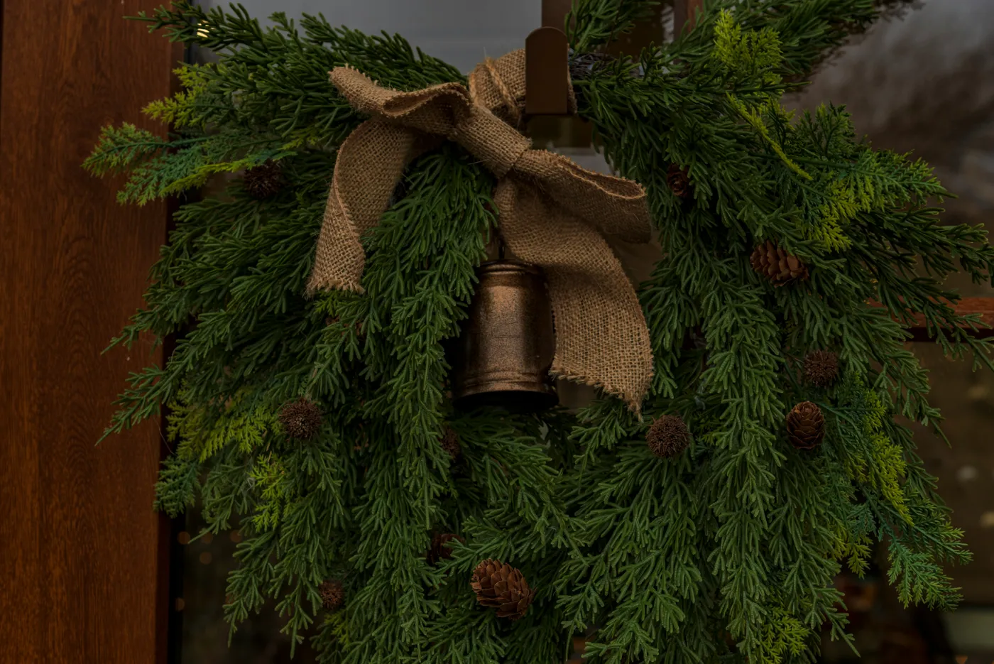 A rustic christmas wreath with pinecones and a bell