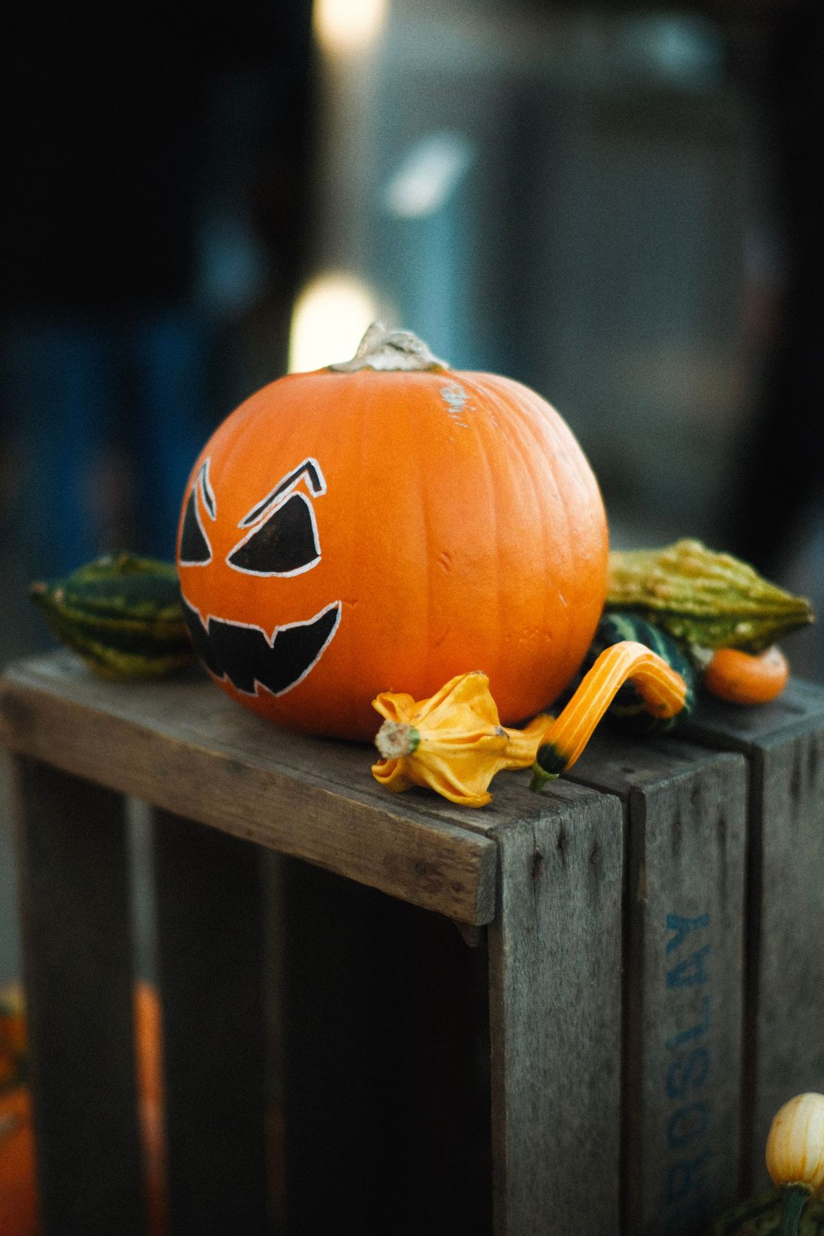 A spooky jack-o'-lantern sits atop a rustic crate with gourds, embodying Halloween festivities.