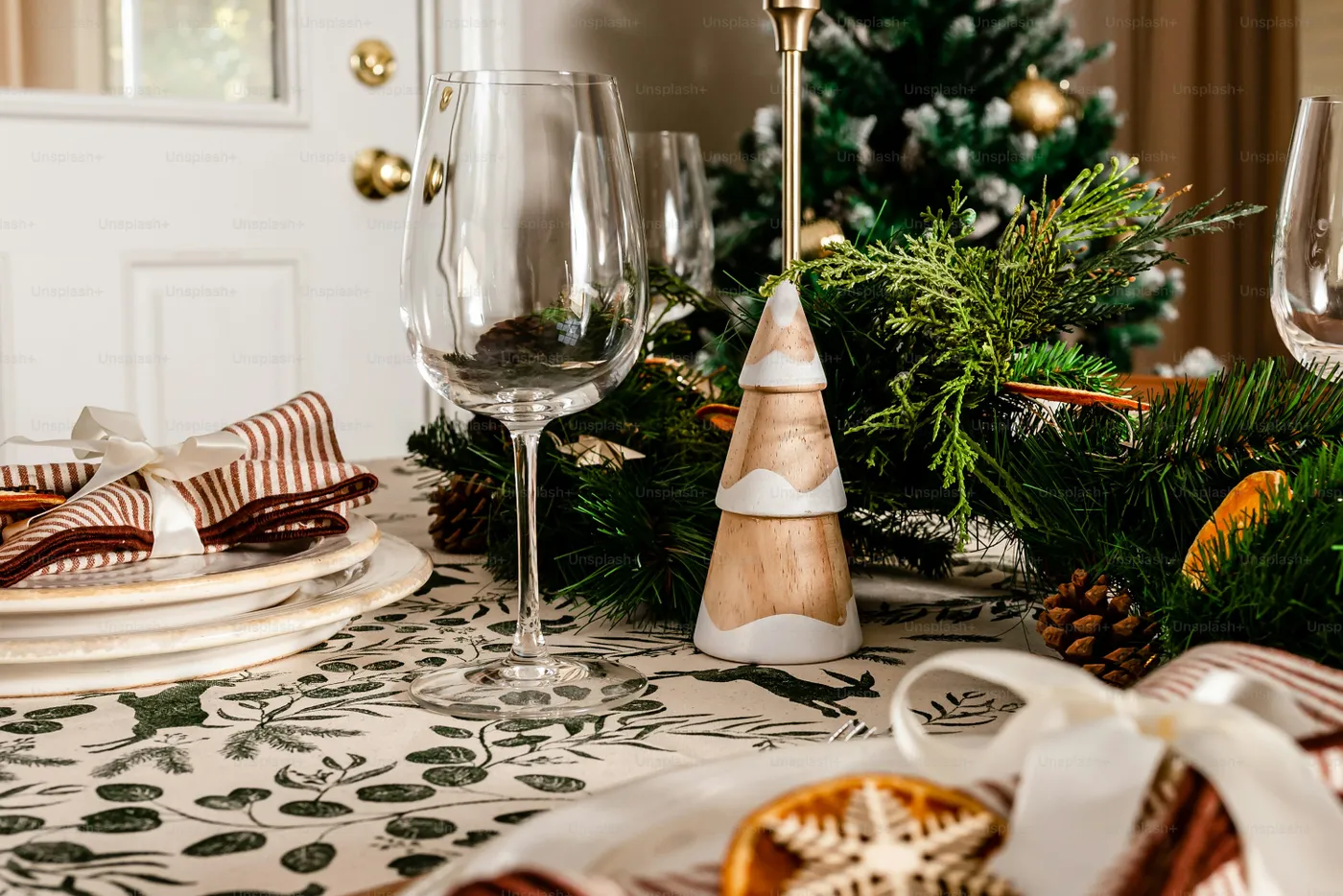 A table set for christmas with wine glasses and plates - Photo on Unsplash+