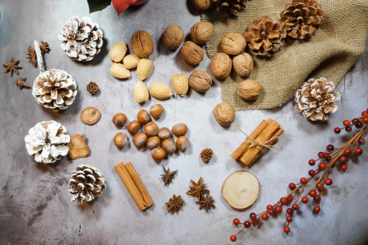 A top-down view of nuts, pinecones, and cinnamon on a rustic background.