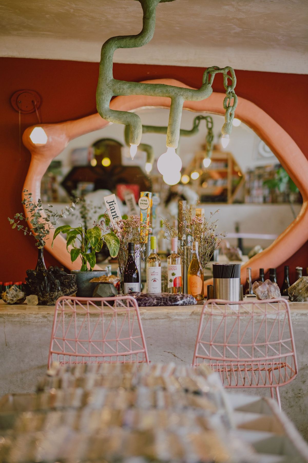 A vibrant dining space featuring pink chairs, eclectic decor, and lush greenery.