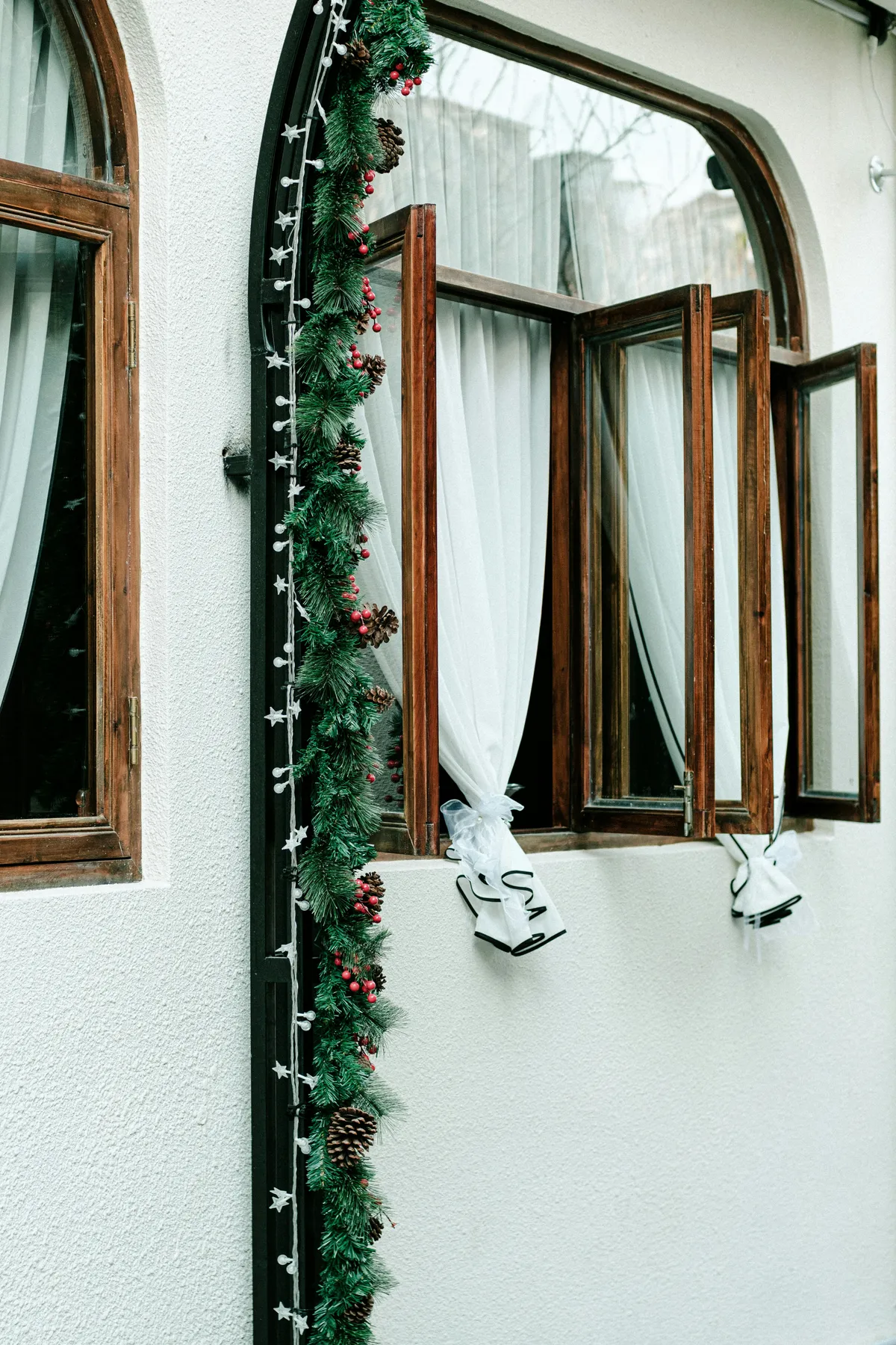 a window with a christmas garland on the outside of it