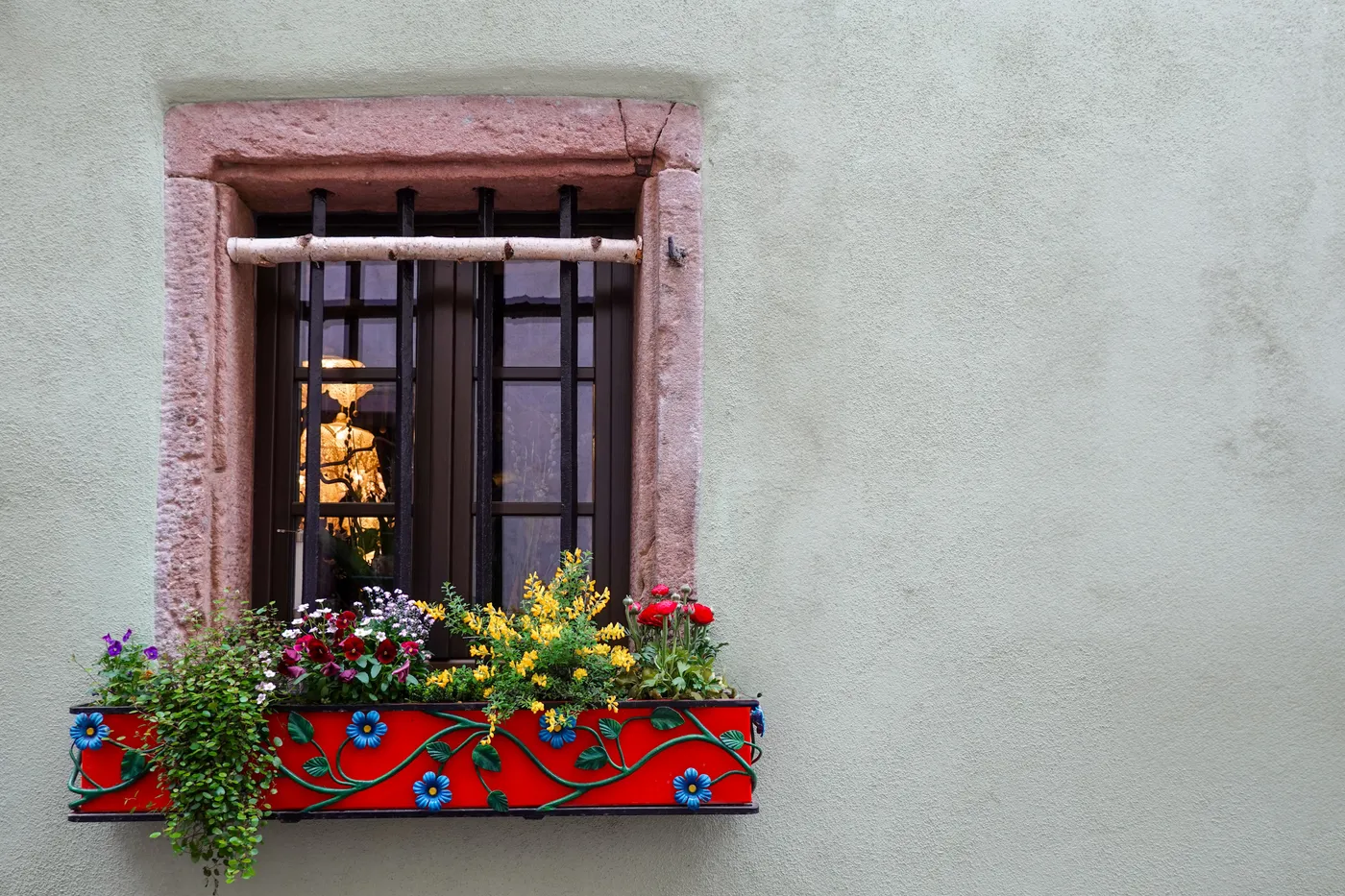 A window with vibrant flower box on an exterior wall. Captures colorful charm.