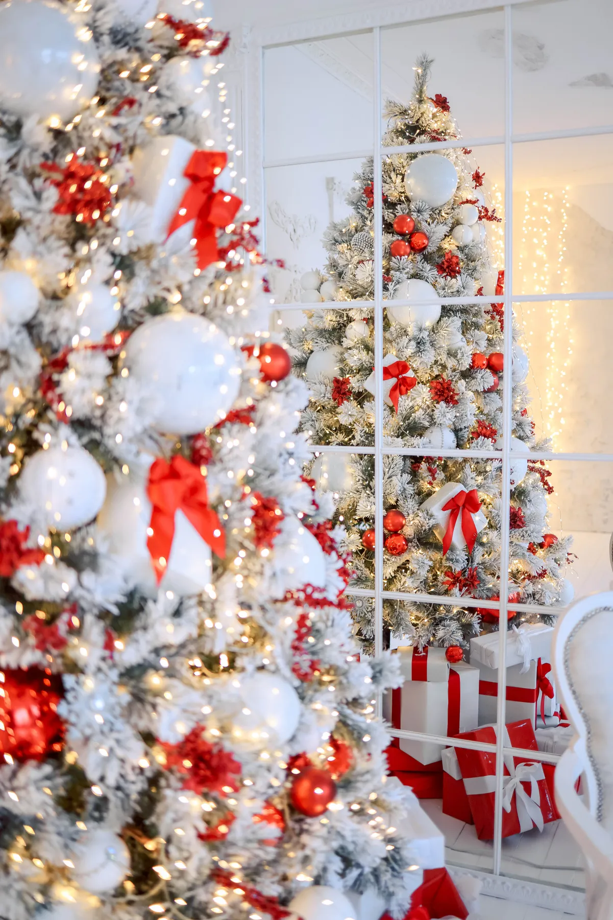 Beautiful Christmas tree adorned with red and white decorations, reflecting in a mirror.