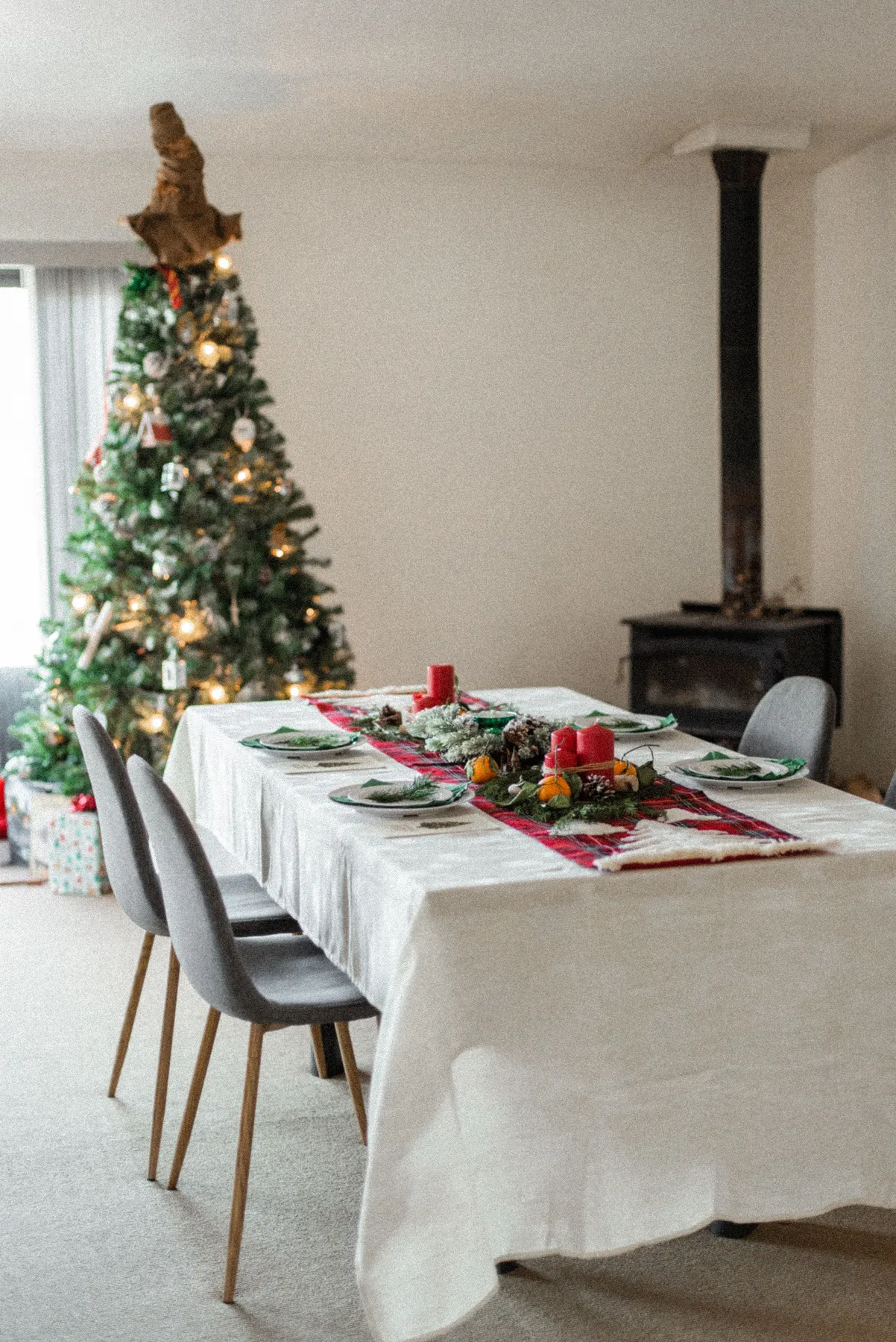 Beautiful decorations of Christmas tree and table with candles served for festive dinner in modern light living room during daytime