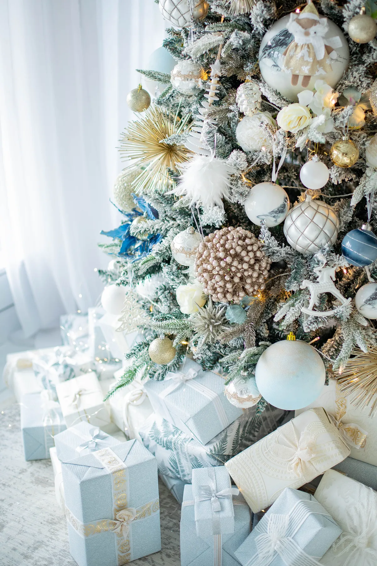Beautifully decorated Christmas tree with white and gold ornaments and neatly wrapped presents.