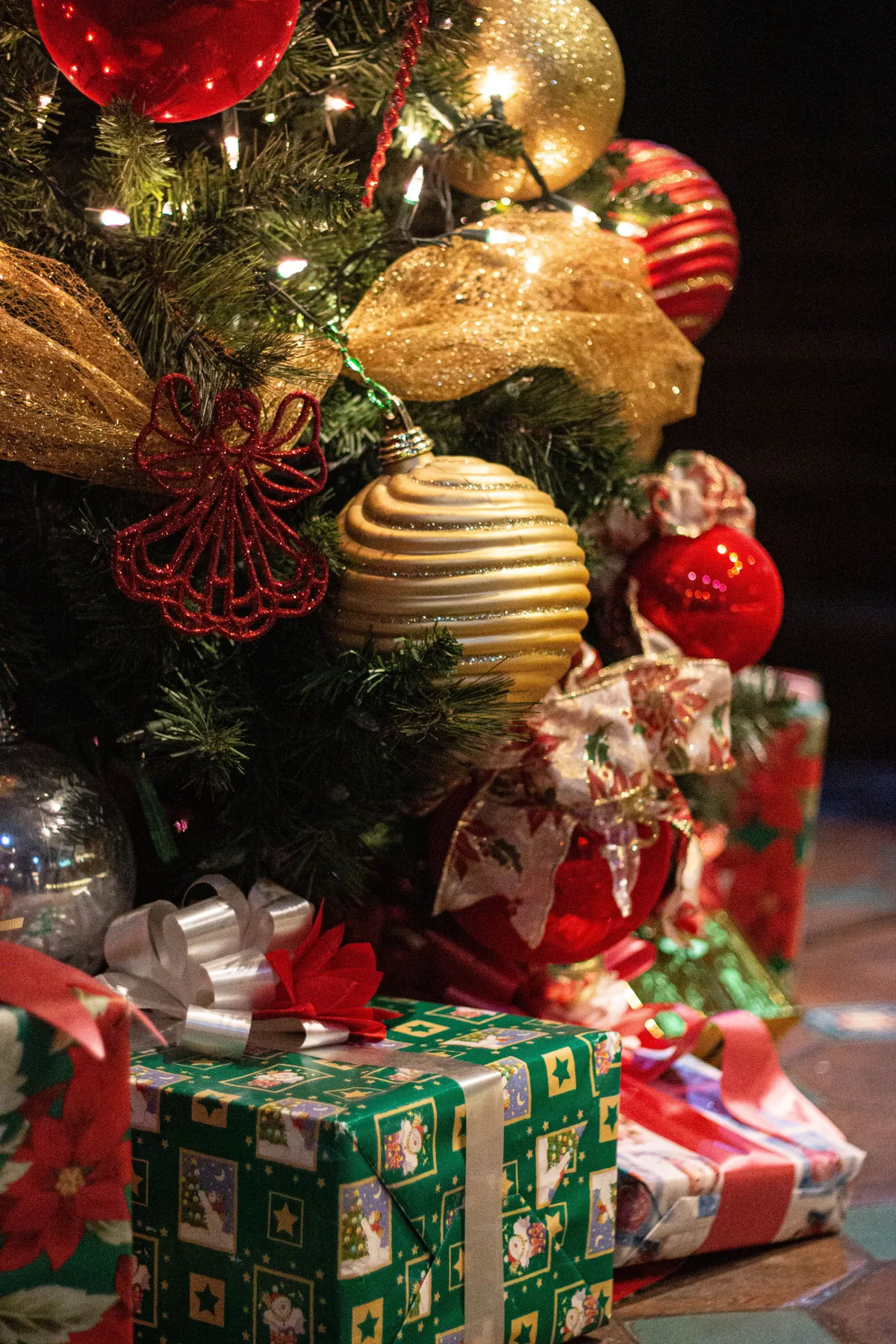 Beautifully decorated Christmas tree with gifts underneath, adorned with festive ornaments and lights.