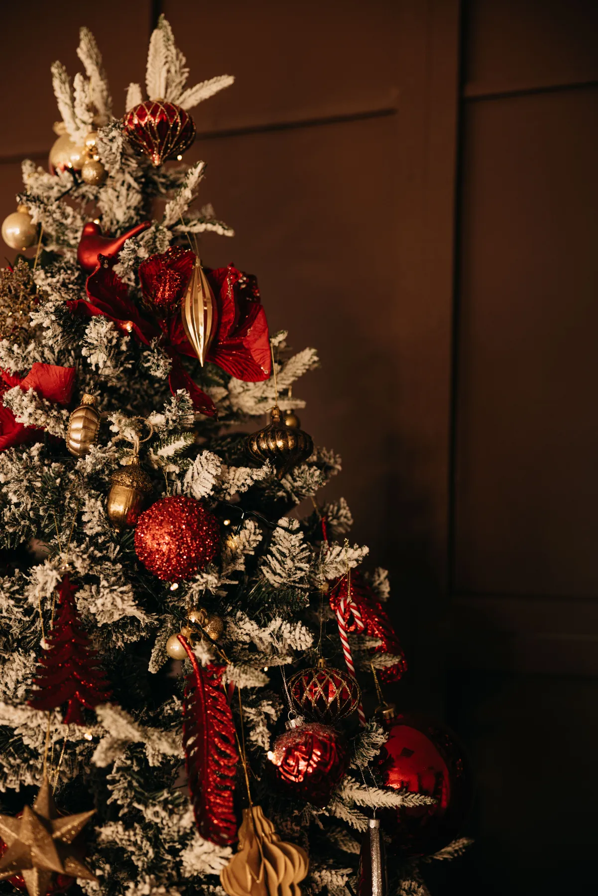 Beautifully decorated Christmas tree with red and gold ornaments in a cozy indoor setting.