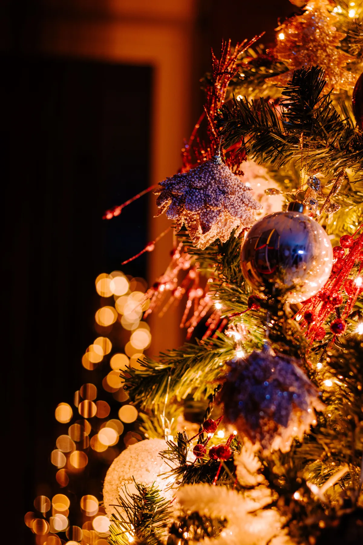 Beautifully decorated Christmas tree with shimmering ornaments and warm bokeh lights.