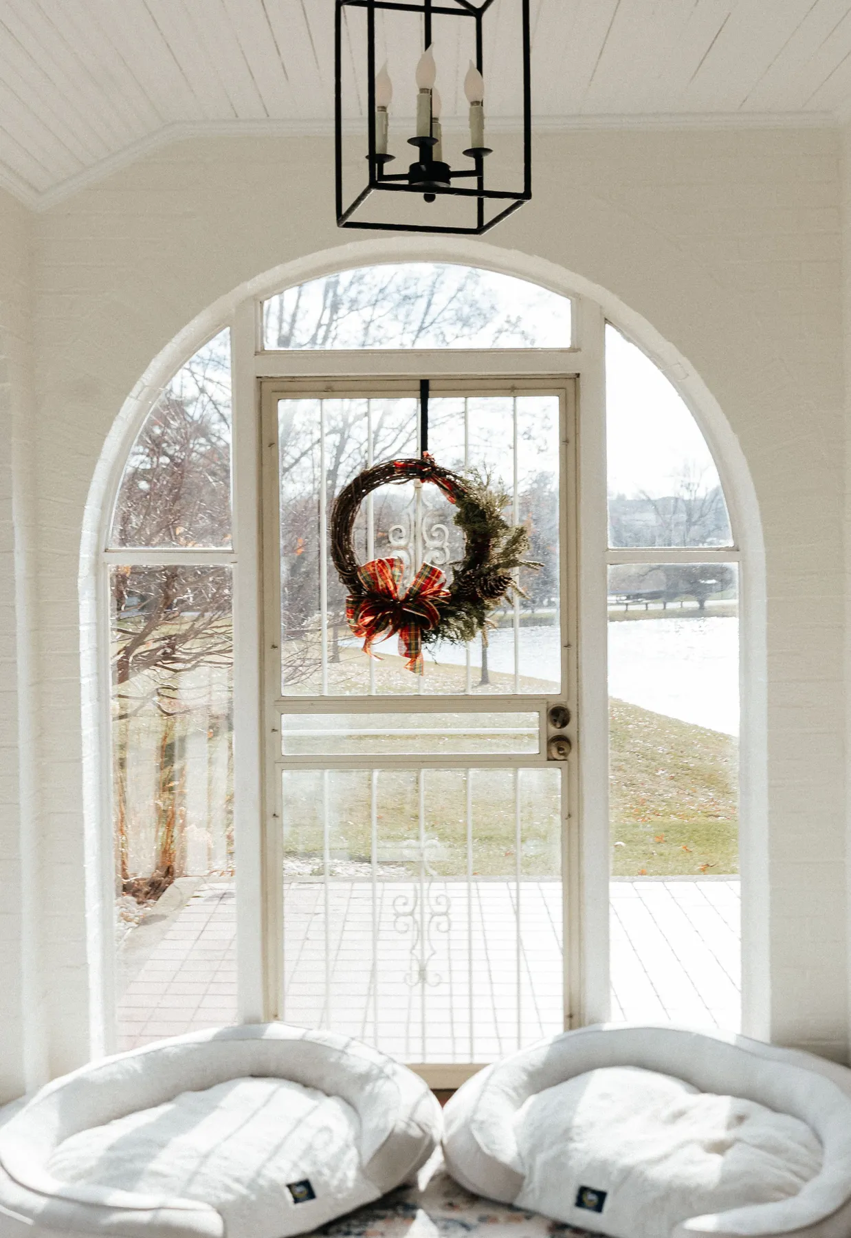 Bright interior with a festive wreath on a glass door, capturing winter tranquility.