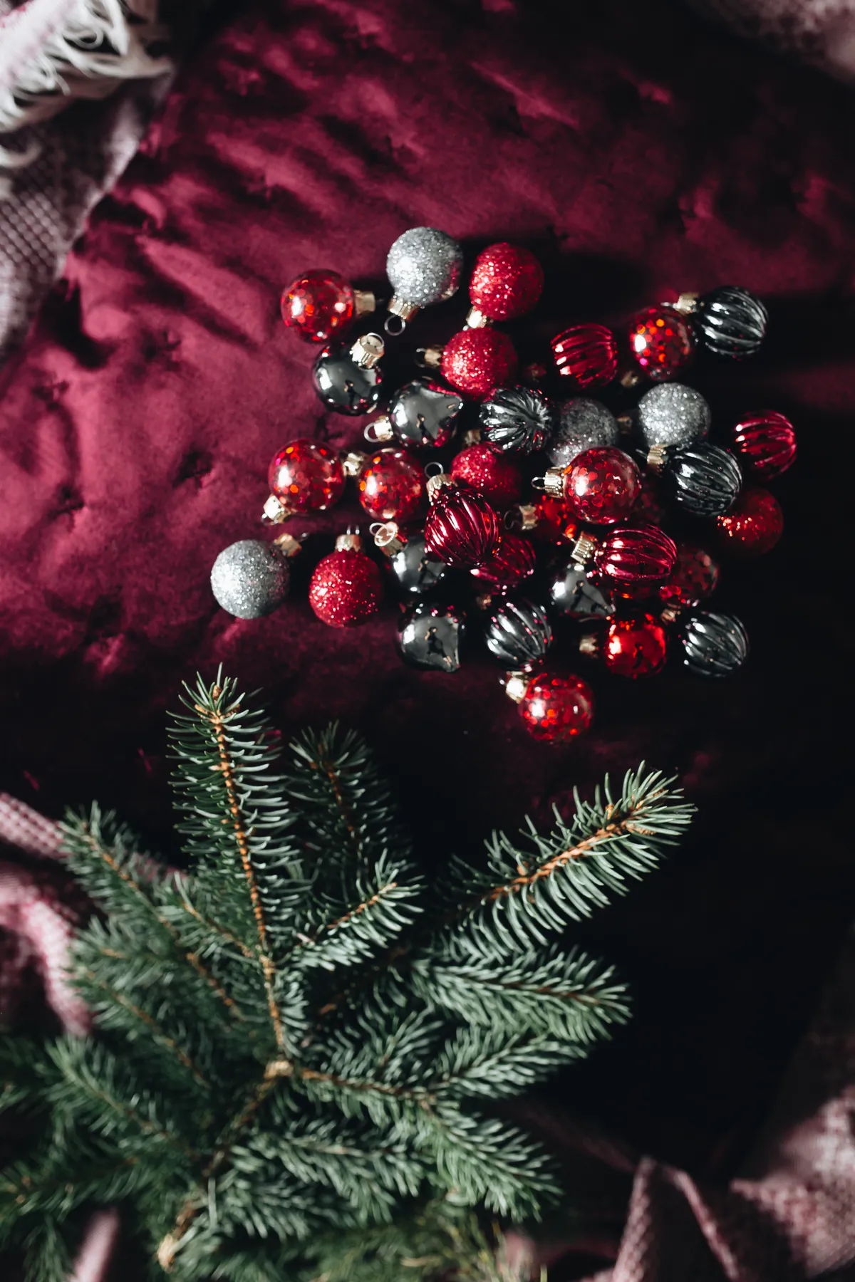Burgundy Christmas Still Life with Baubles, Greenery and Warm Lights. Ideal for holidays and decor projects. Free for commercial use.