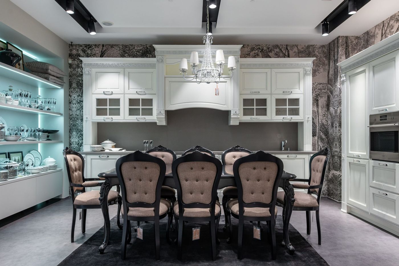 Chairs at table placed in spacious kitchen with oven near white cabinets and storage cupboard with various tableware in apartment