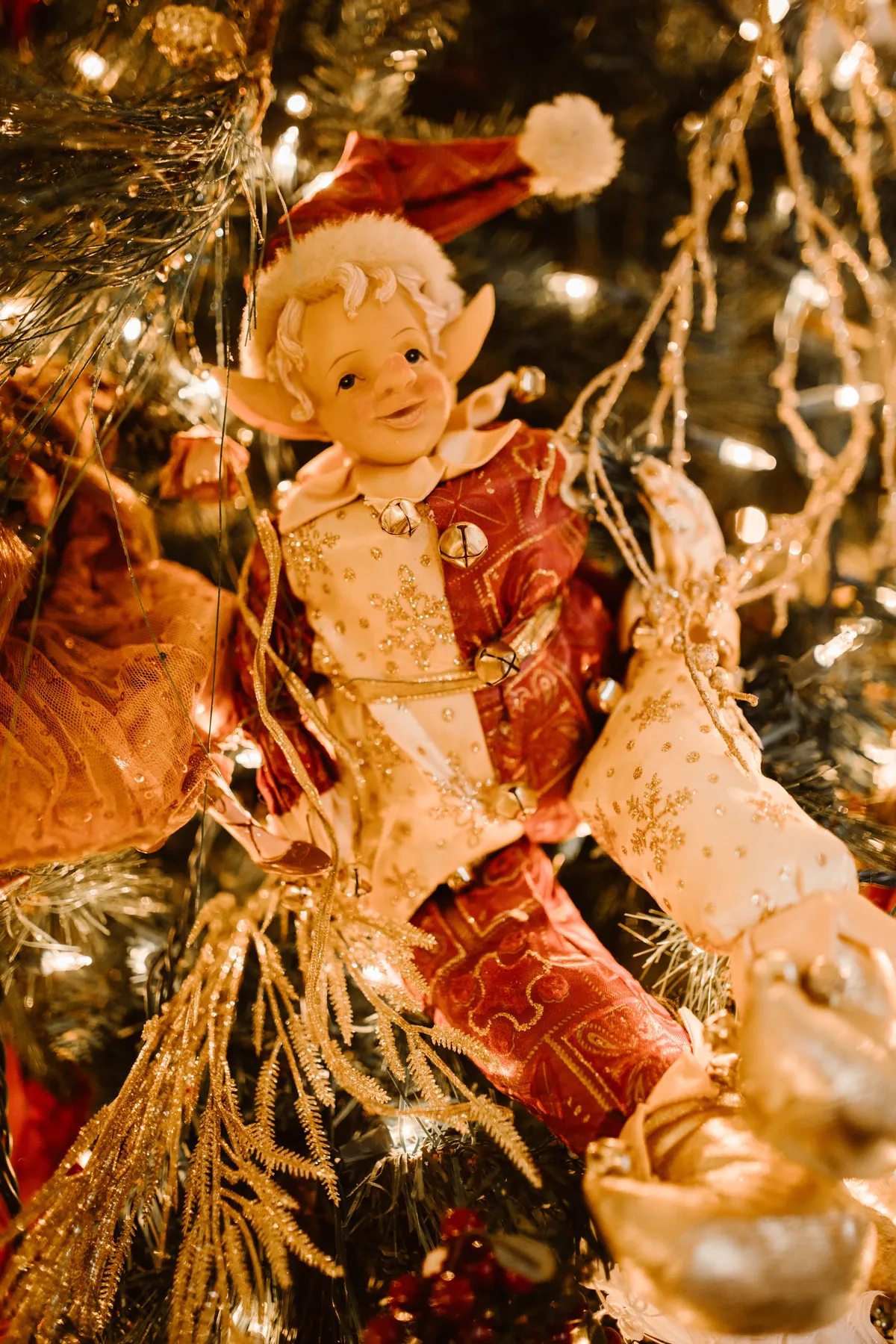 Charming Christmas elf ornament nestled in a beautifully decorated tree with lights.