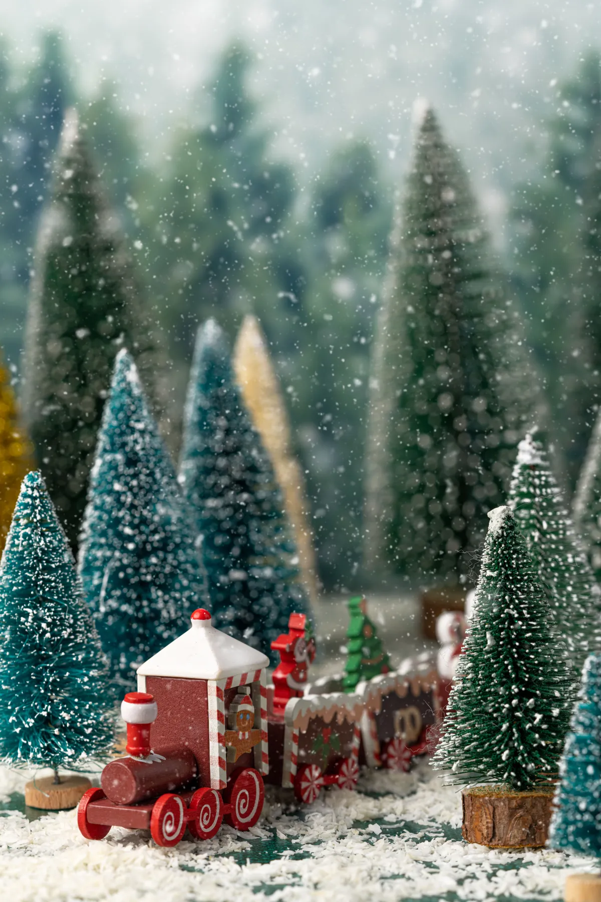 Charming Christmas train set amidst snow-covered model trees in a festive holiday display.