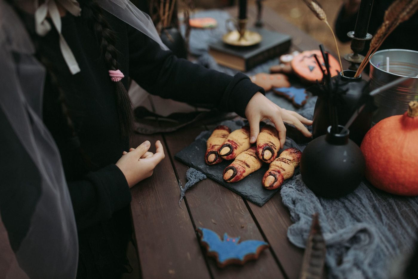 Close-up of Halloween-themed treat table with finger-shaped cookies and pumpkins.