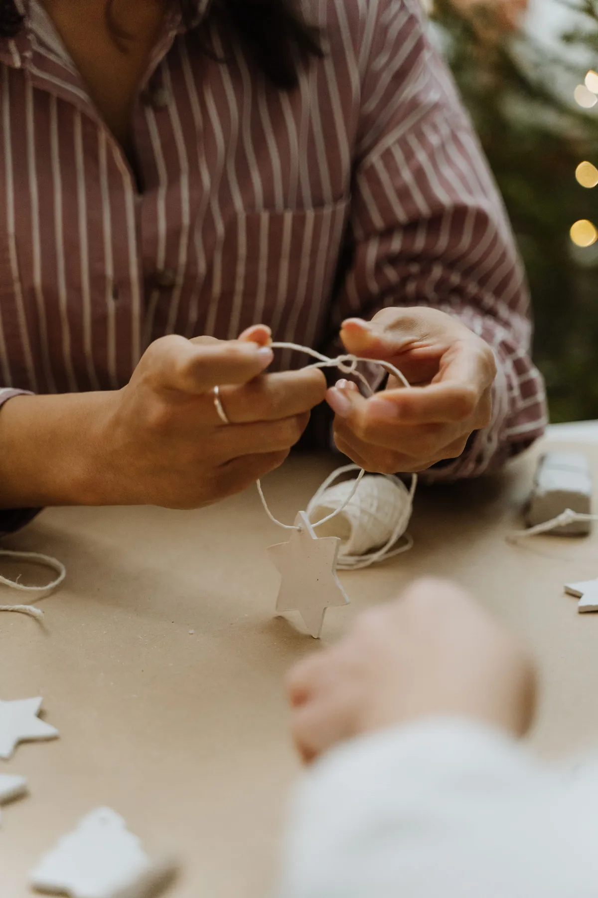 Close-up of hands preparing Christmas star decorations, highlighting creativity and winter festivity.
