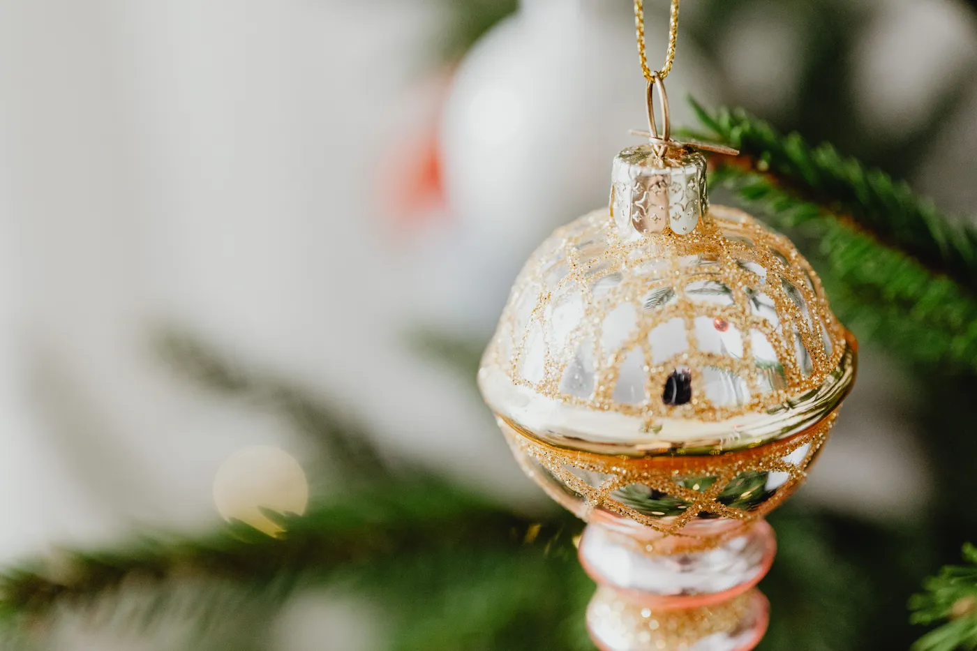 Close-up view of a shimmering gold Christmas ornament hanging on a tree branch, exuding festive charm.