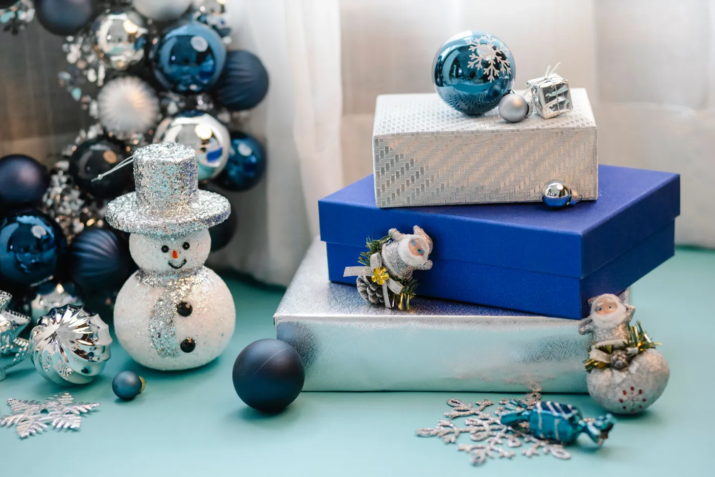 Collection of decorative balls and snowman near shiny presents on blue surface in room