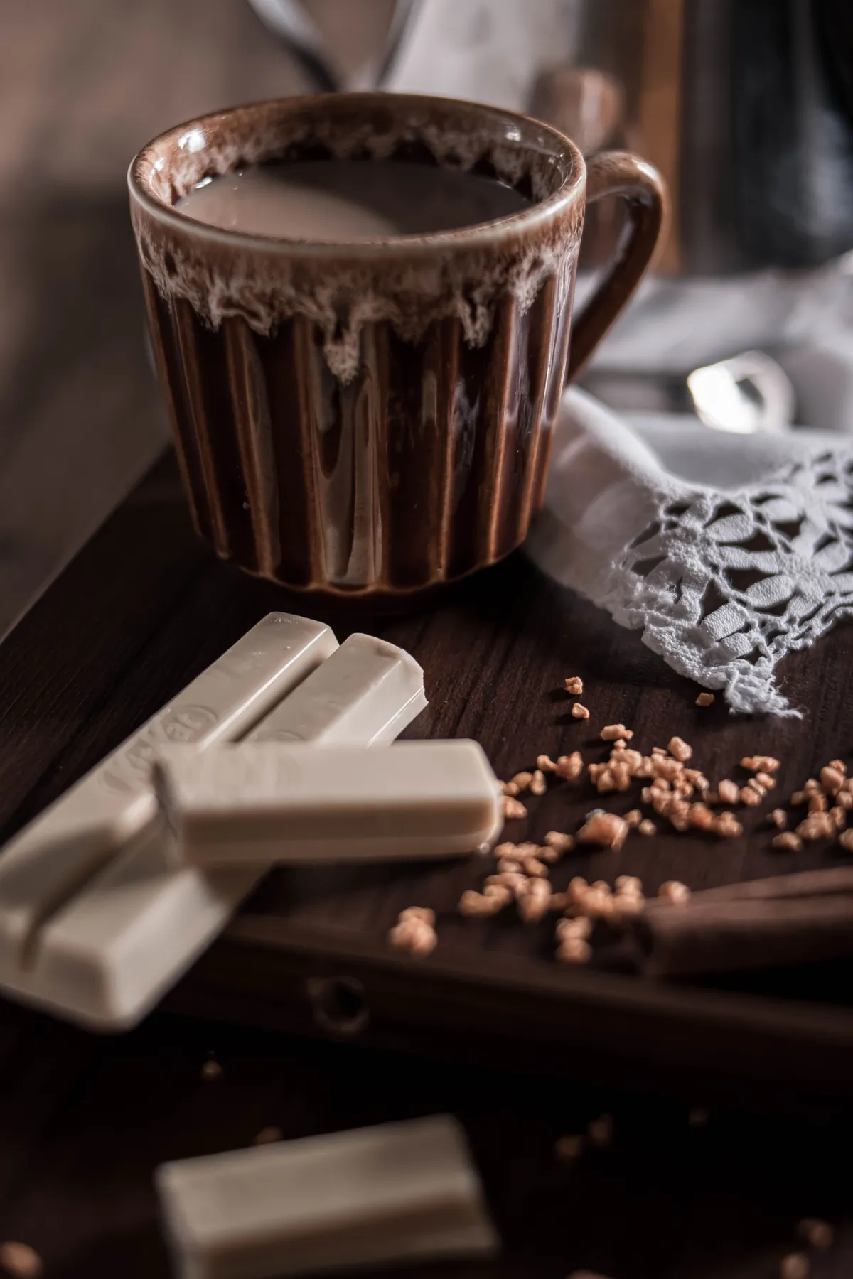 Cozy setup of a coffee cup with white chocolate bars on a wooden tray.