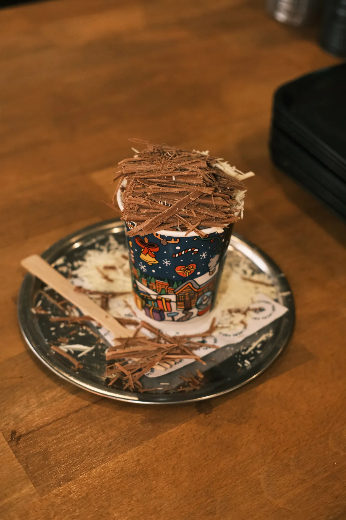 Delicious hot chocolate topped with rich shaved chocolate on a wooden table.