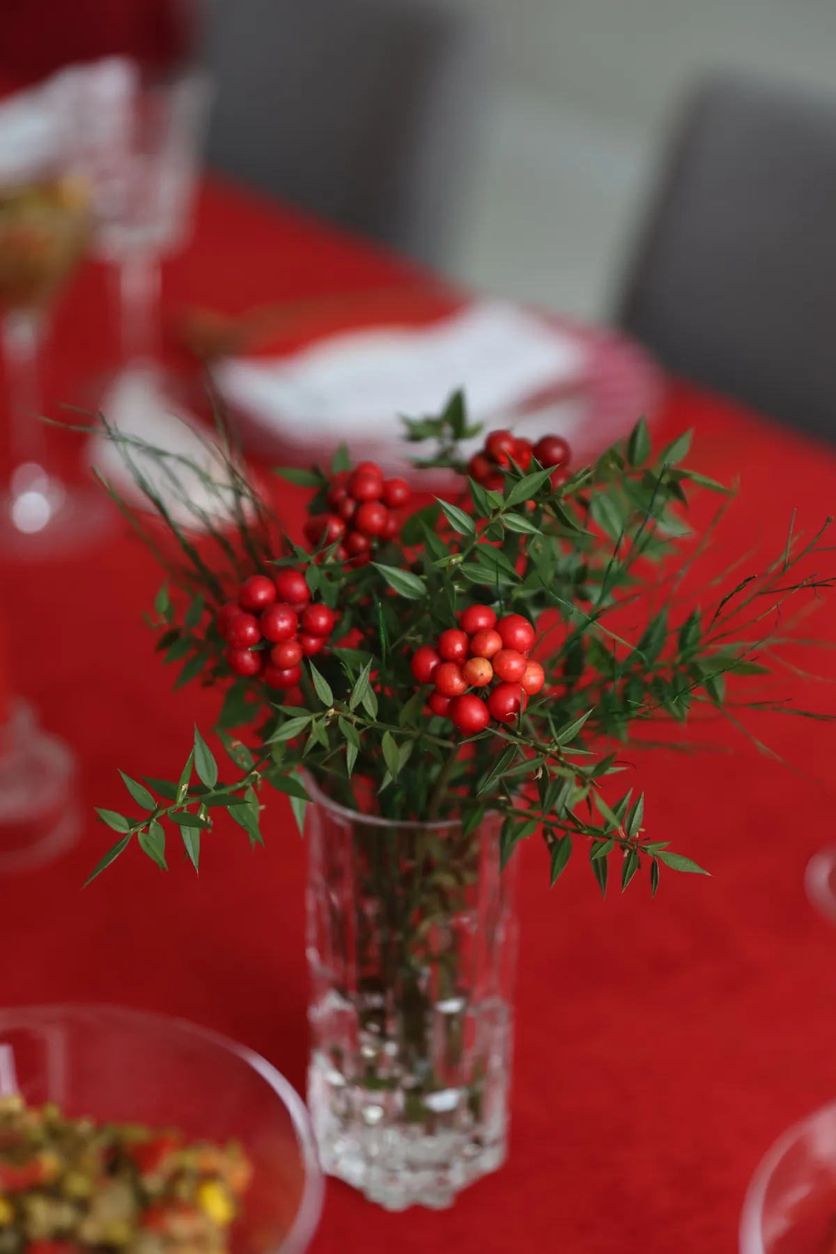 Elegant vase with red berries on a festive table setting for holidays.