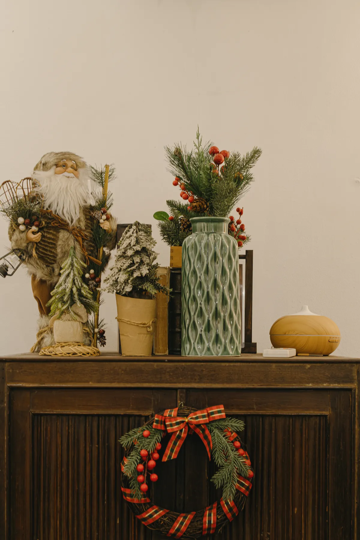Festive Christmas decoration featuring a Santa figurine and wreath in a warm indoor setting.