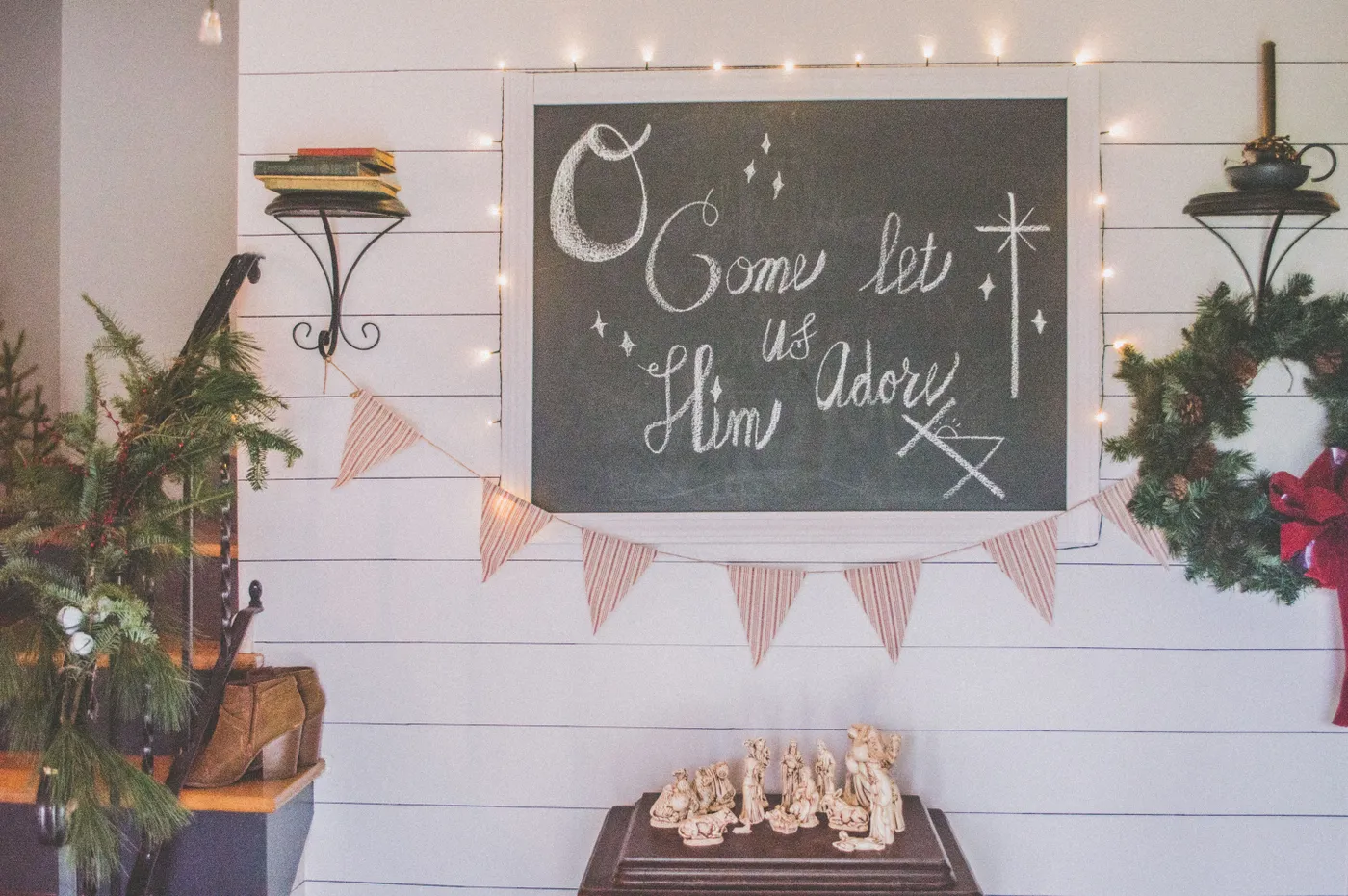 Festive Christmas setup featuring a chalkboard with holiday message, wreath, and nativity scene.