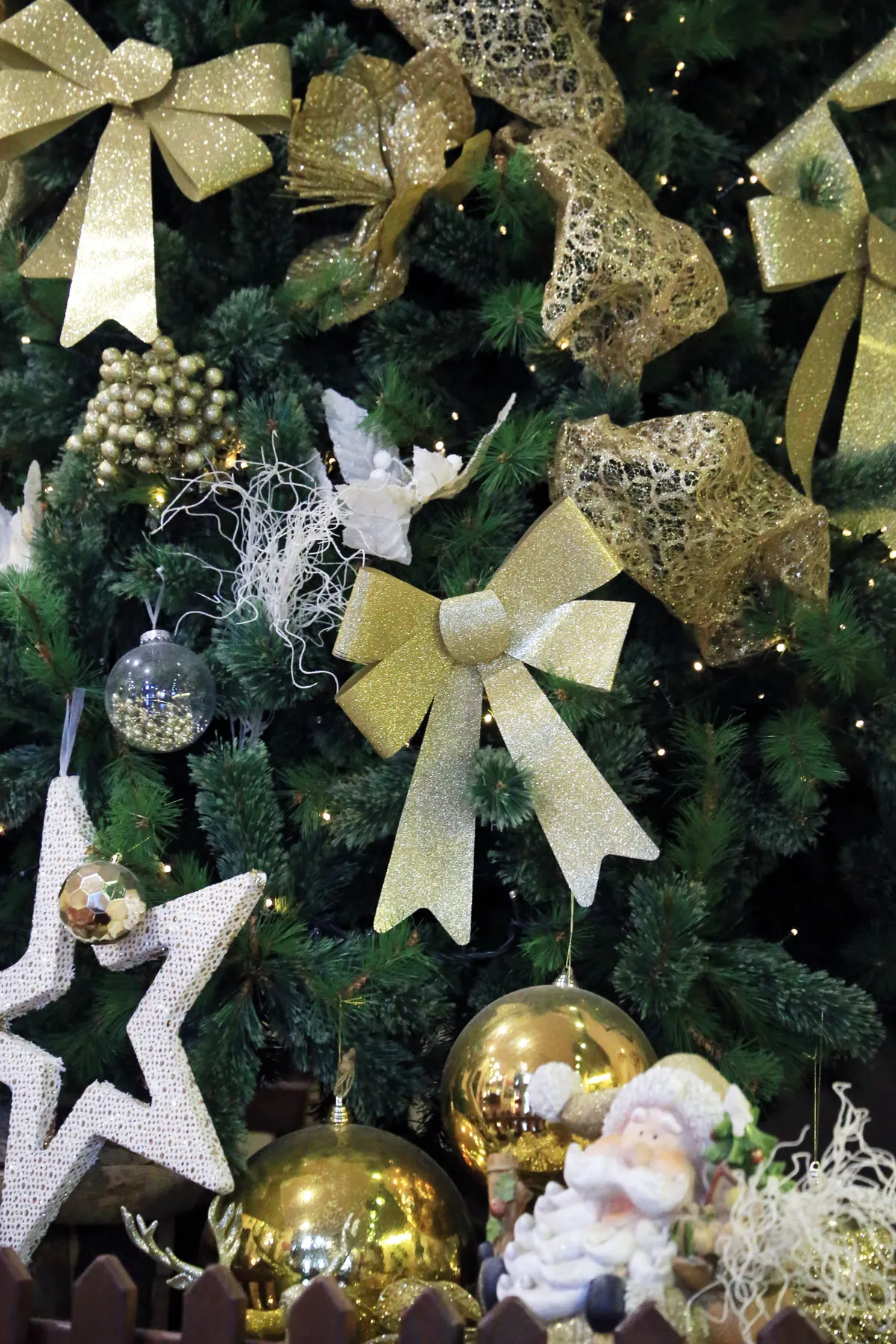 Festive Christmas tree adorned with gold bows and ornaments, highlighting holiday elegance and warmth.