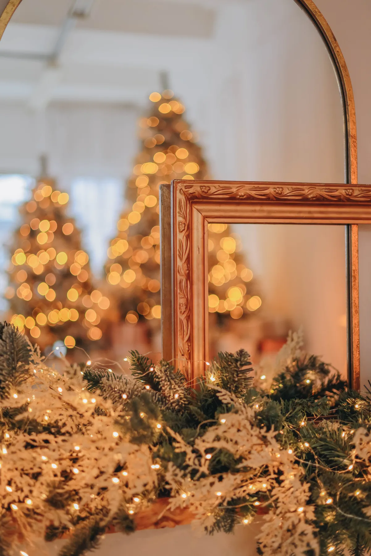 Festive scene with Christmas trees and lights reflecting in a mirror, creating a warm holiday ambiance.