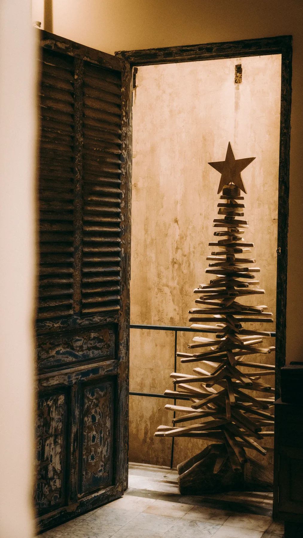 Intricately crafted wooden Christmas tree with star indoors, rustic setting.