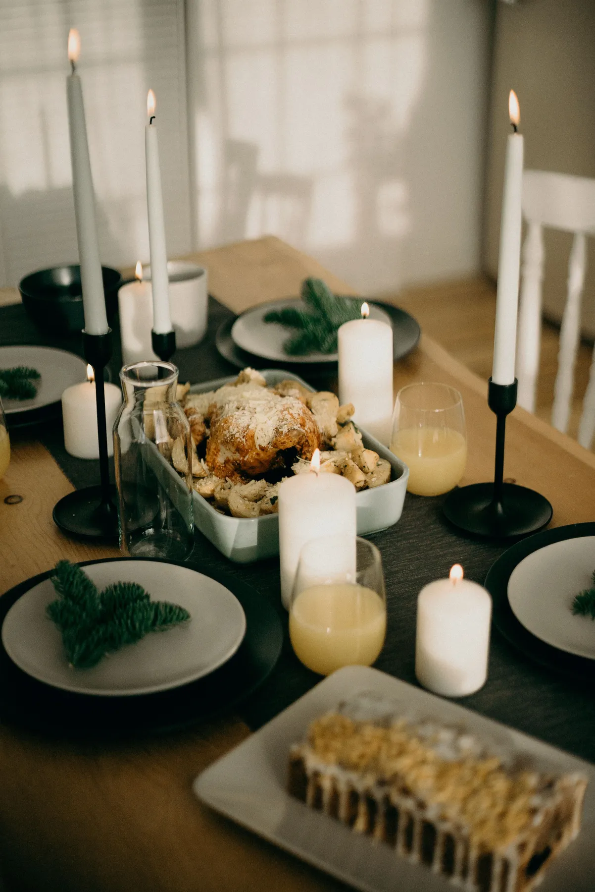 Inviting dining setup with candles, roast chicken, and cake, perfect for a festive holiday gathering.