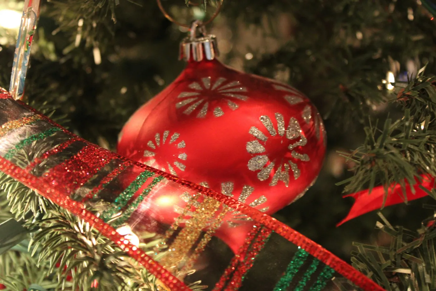 Red christmas ornament with glittery floral pattern on tree