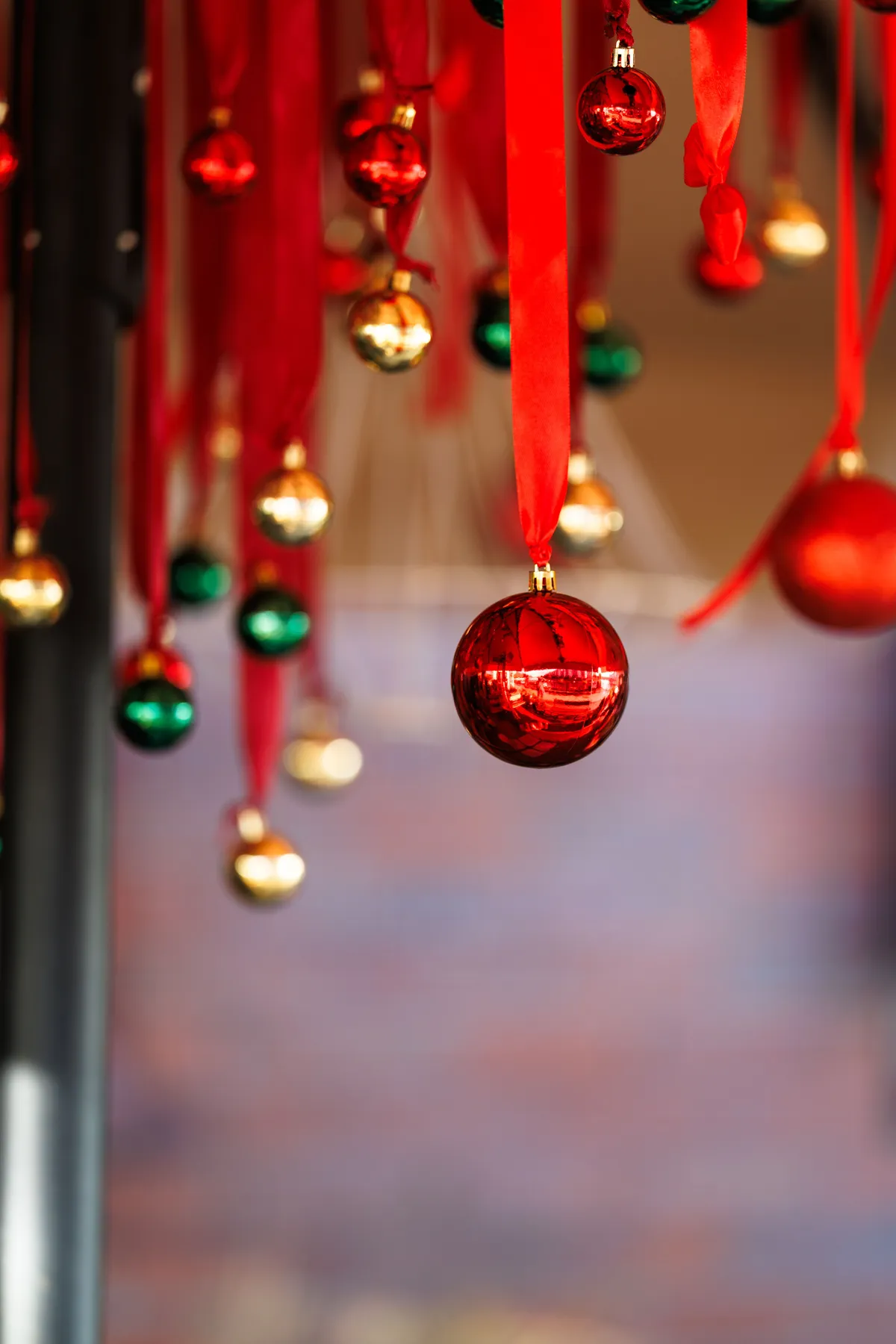 Red, green, and gold Christmas ornaments hanging with ribbons creating a festive holiday atmosphere.