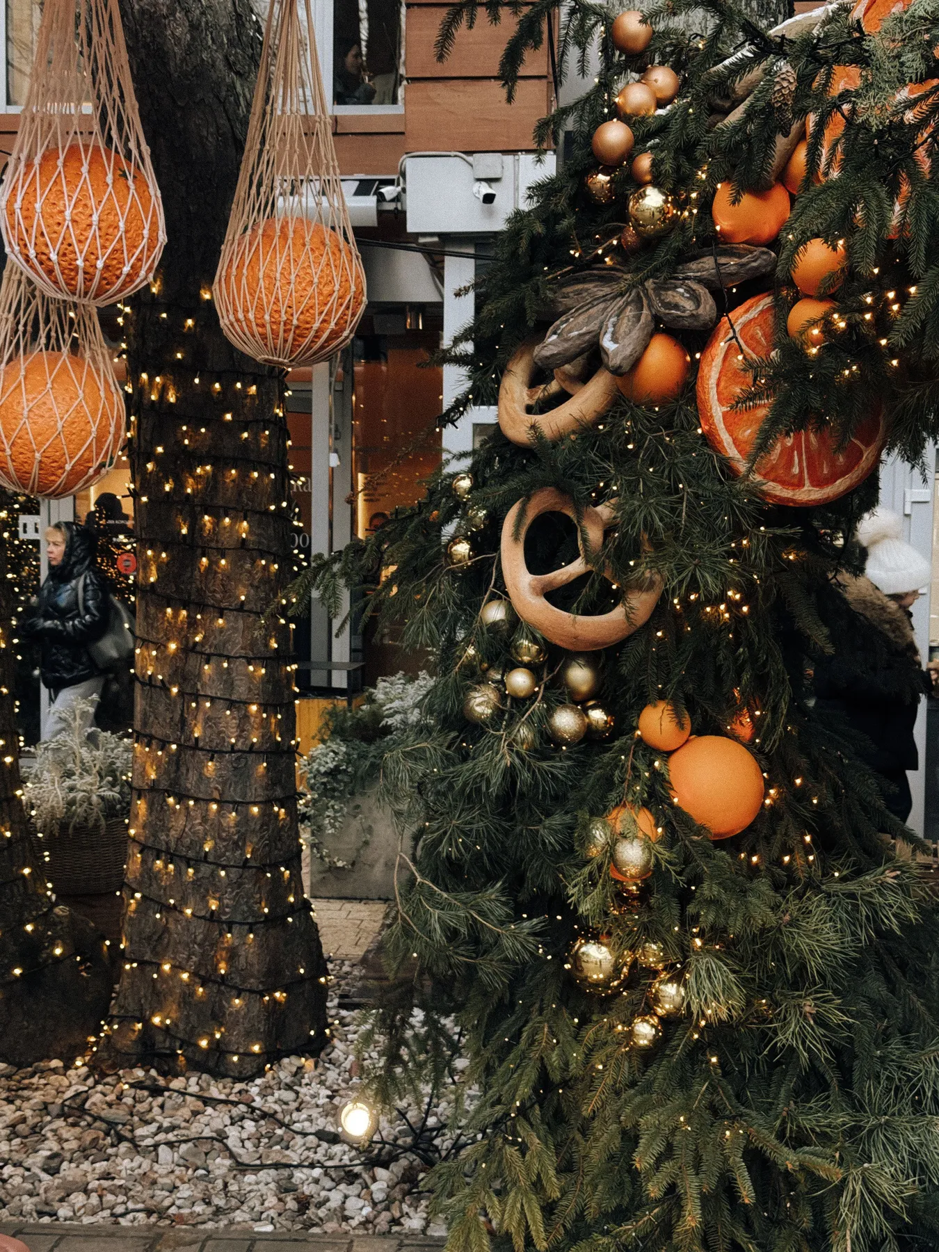 Rustic Christmas decorations with oranges and lights outdoors, creating festive ambience.