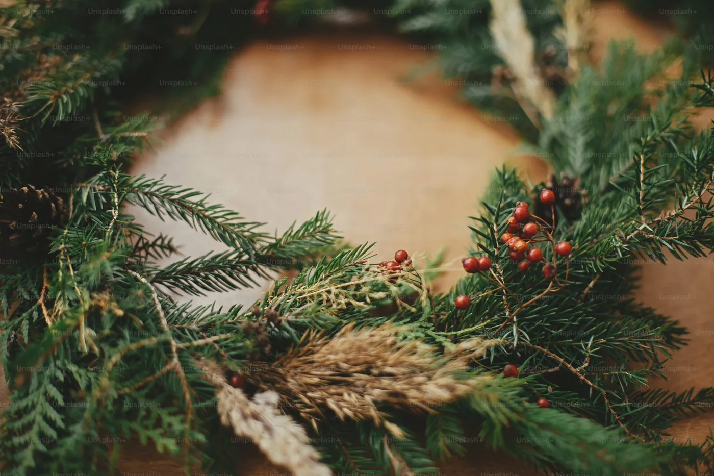 Rustic Christmas wreath detail closeup. Fir branches, pine cones, berries on wooden table. Authentic stylish still life. Making Christmas wreath - Photo on Unsplash+