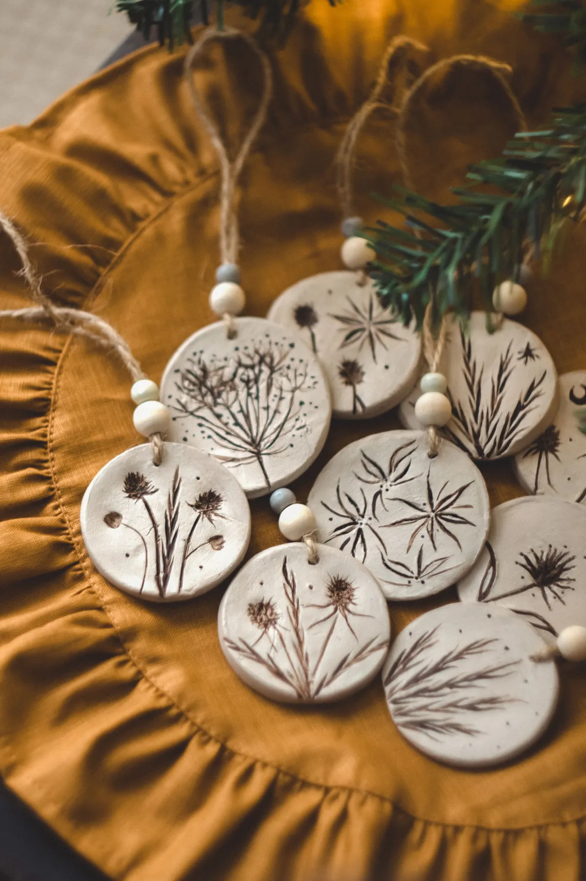 Rustic clay ornaments with botanical designs placed on warm fabric, perfect for home decor.