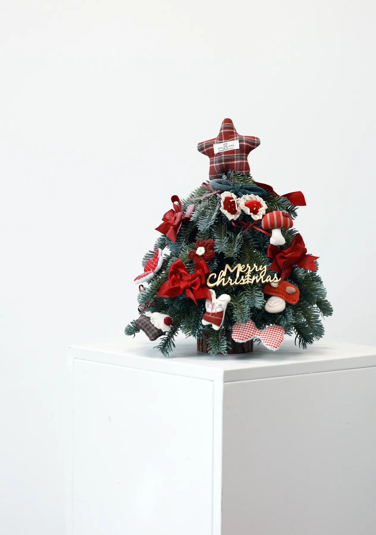 Small decorative Christmas tree adorned with festive ornaments and a plaid star topper.