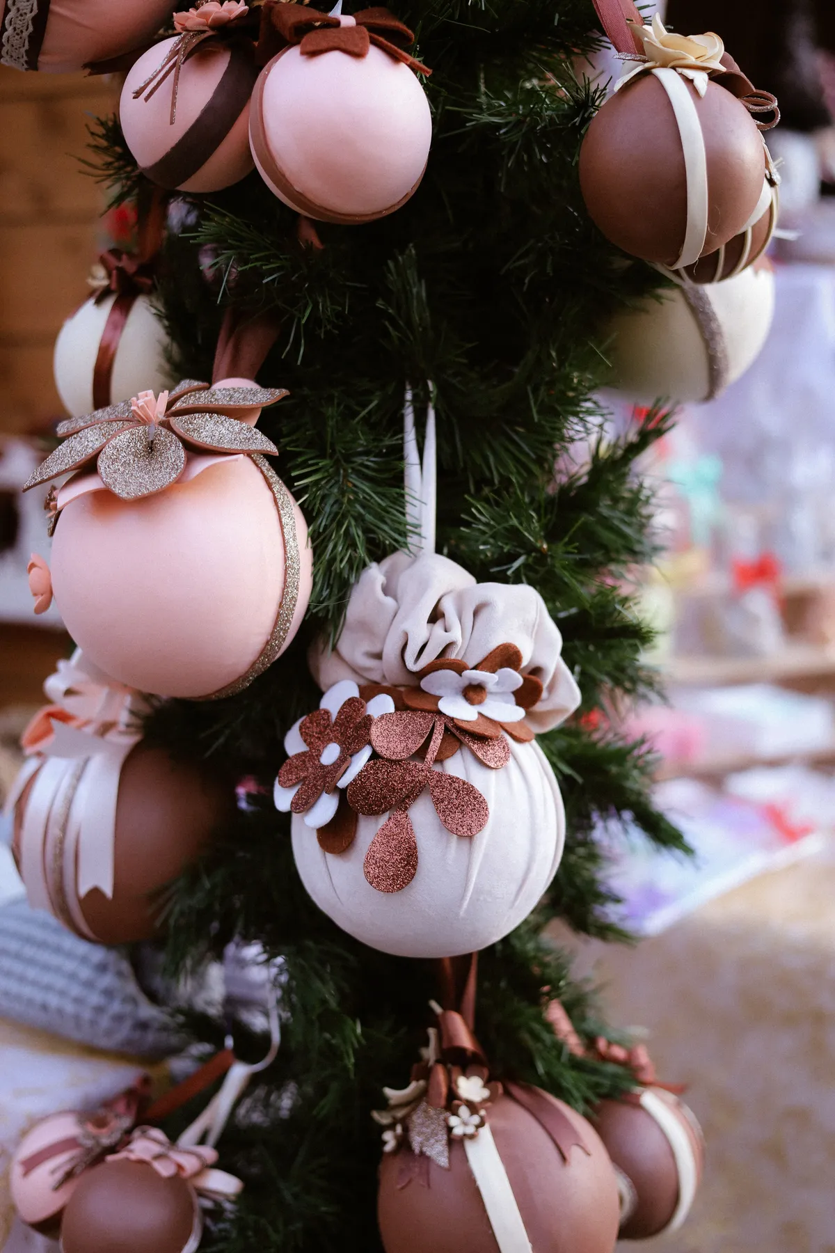 Stylish holiday ornaments in cream and rose gold adorn a Christmas tree, creating a festive ambiance.