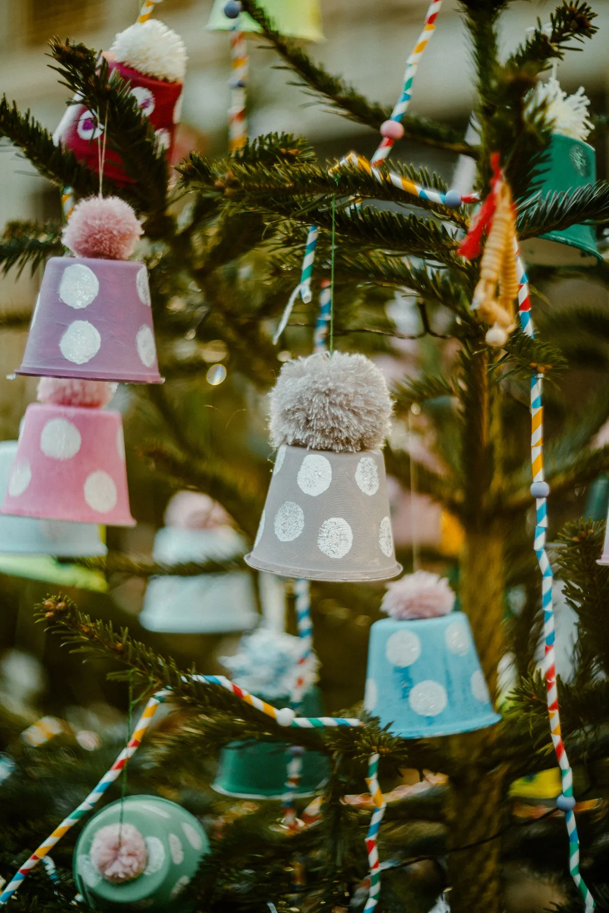 Vibrant Christmas decorations hanging on a pine tree outdoors. Festive and cheerful.