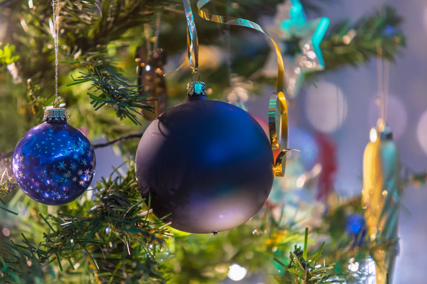 Vibrant Christmas ornaments on a festive tree, capturing holiday spirit with shimmering blue and gold tones.
