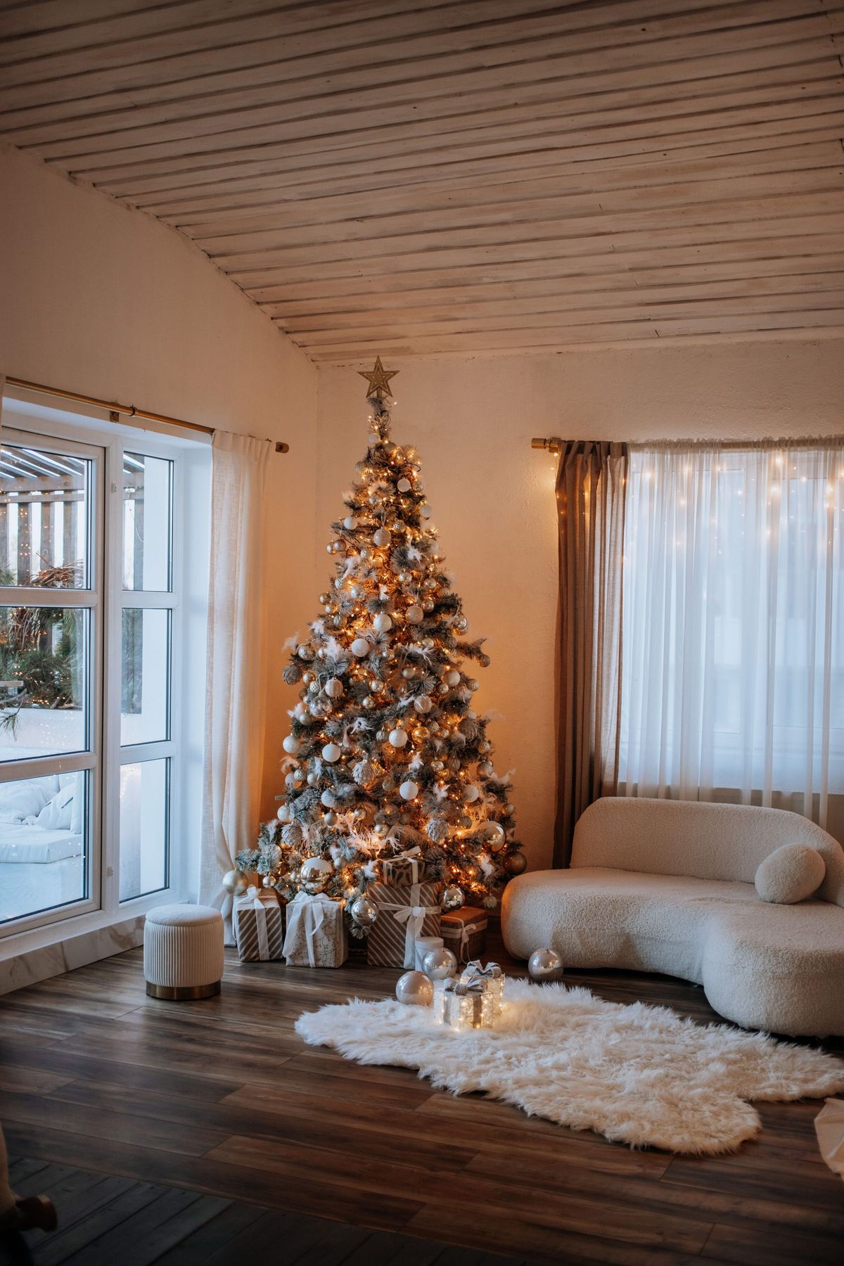 Warm and cozy living room featuring a beautifully decorated Christmas tree with presents.