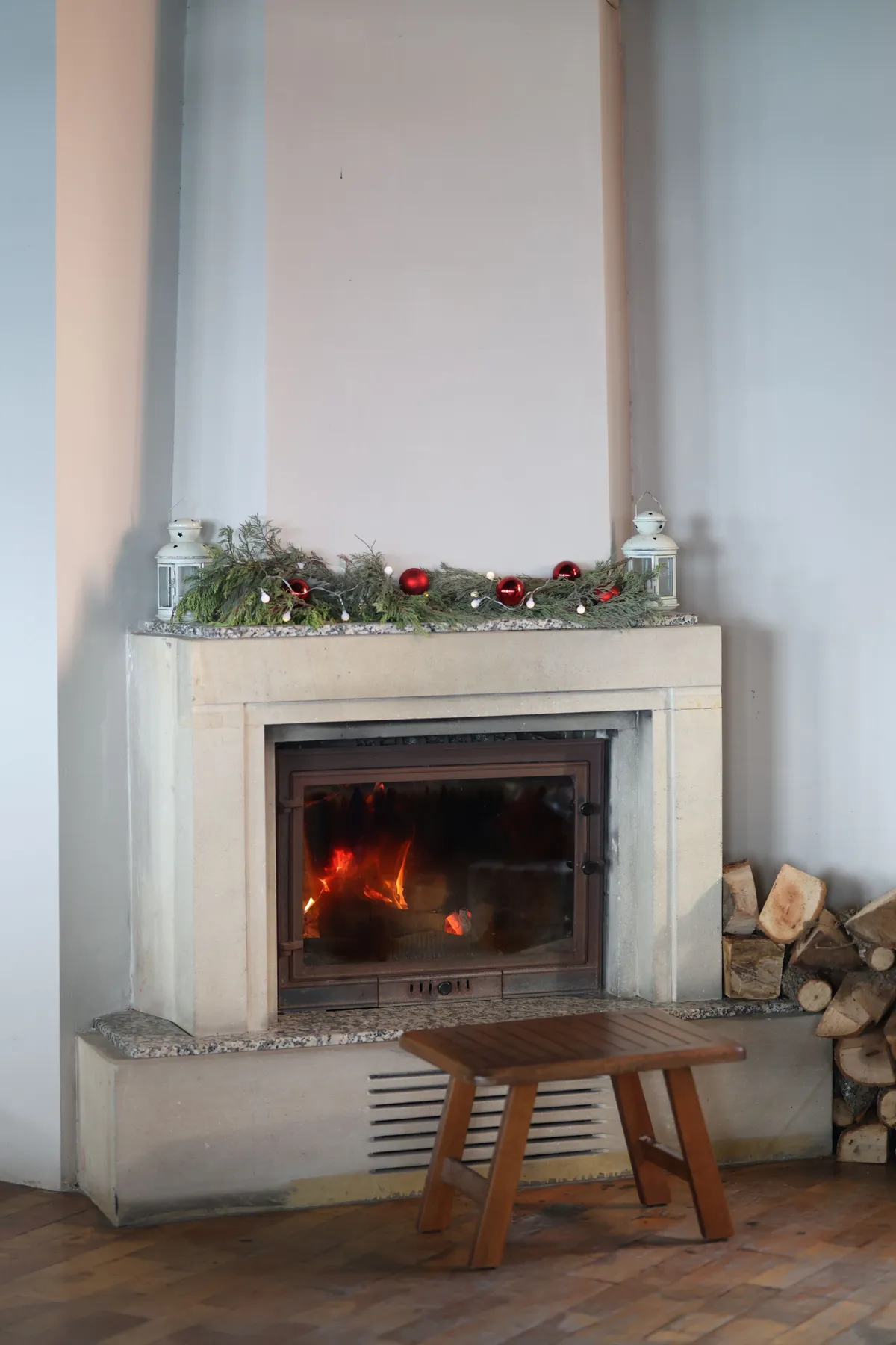 Warm and inviting indoor fireplace decorated with Christmas ornaments and greenery.