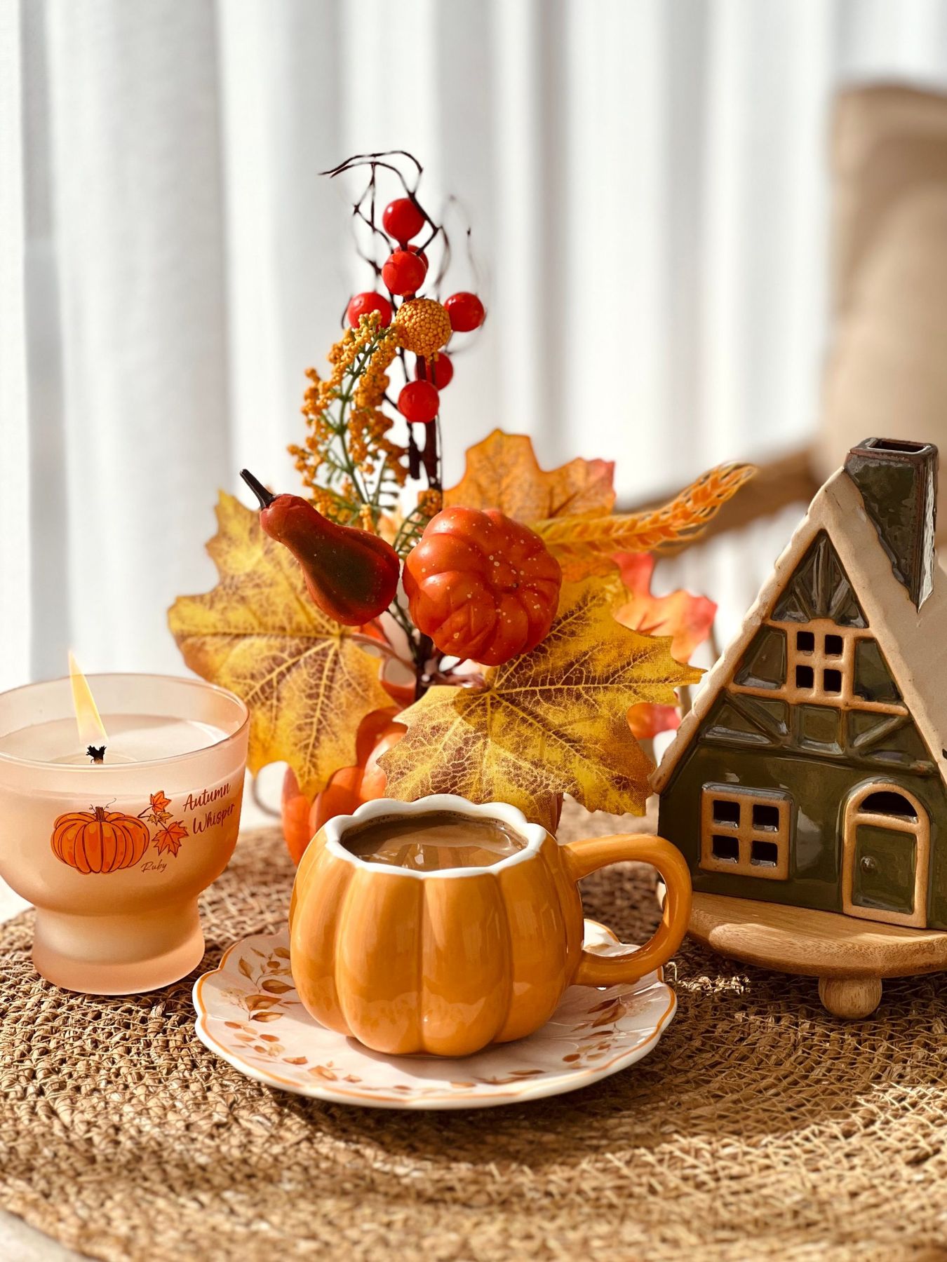 Warm autumn scene featuring pumpkin decor and candle on woven mat.