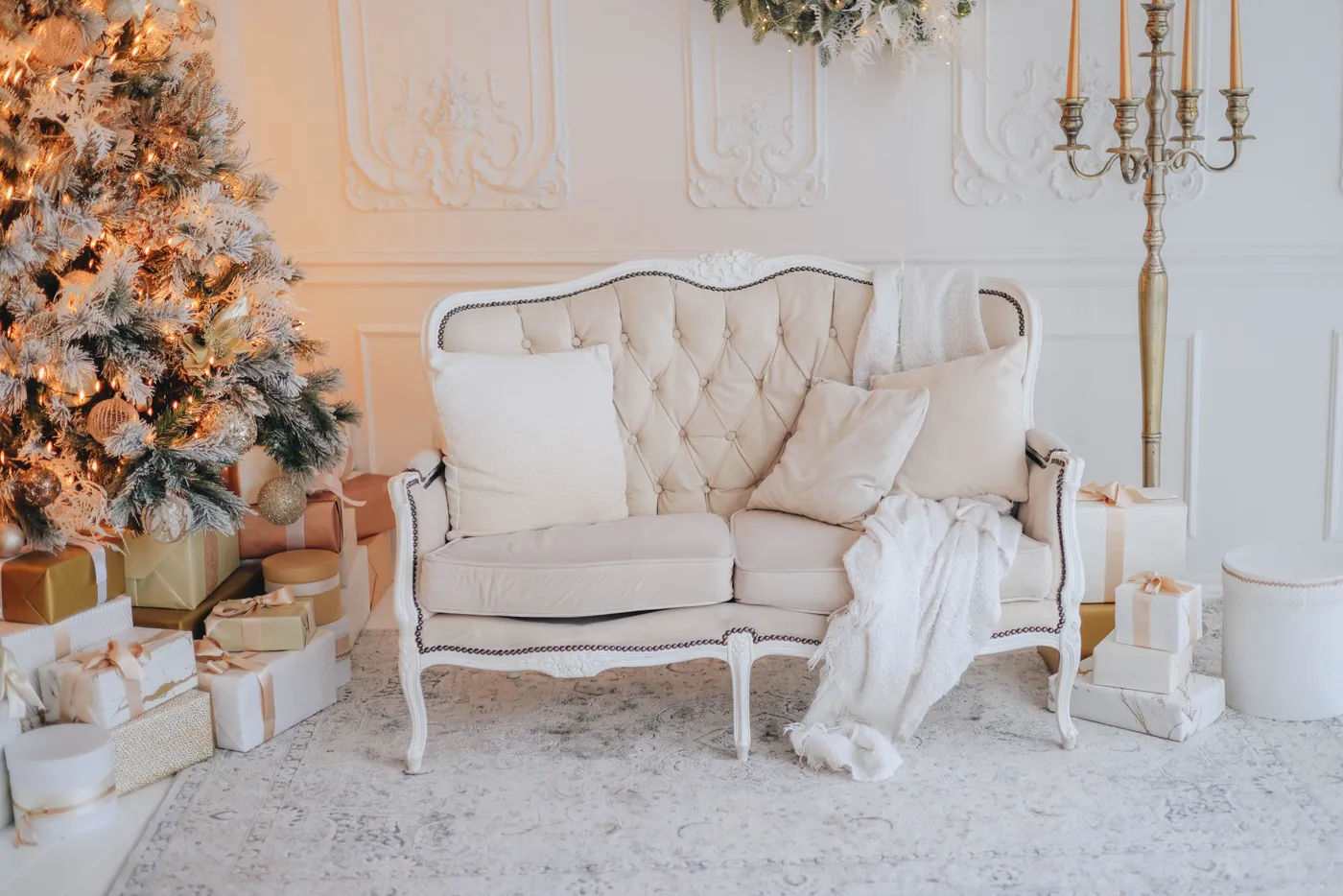 Warm, elegant living room decorated for Christmas with tree, gifts, and cozy sofa.