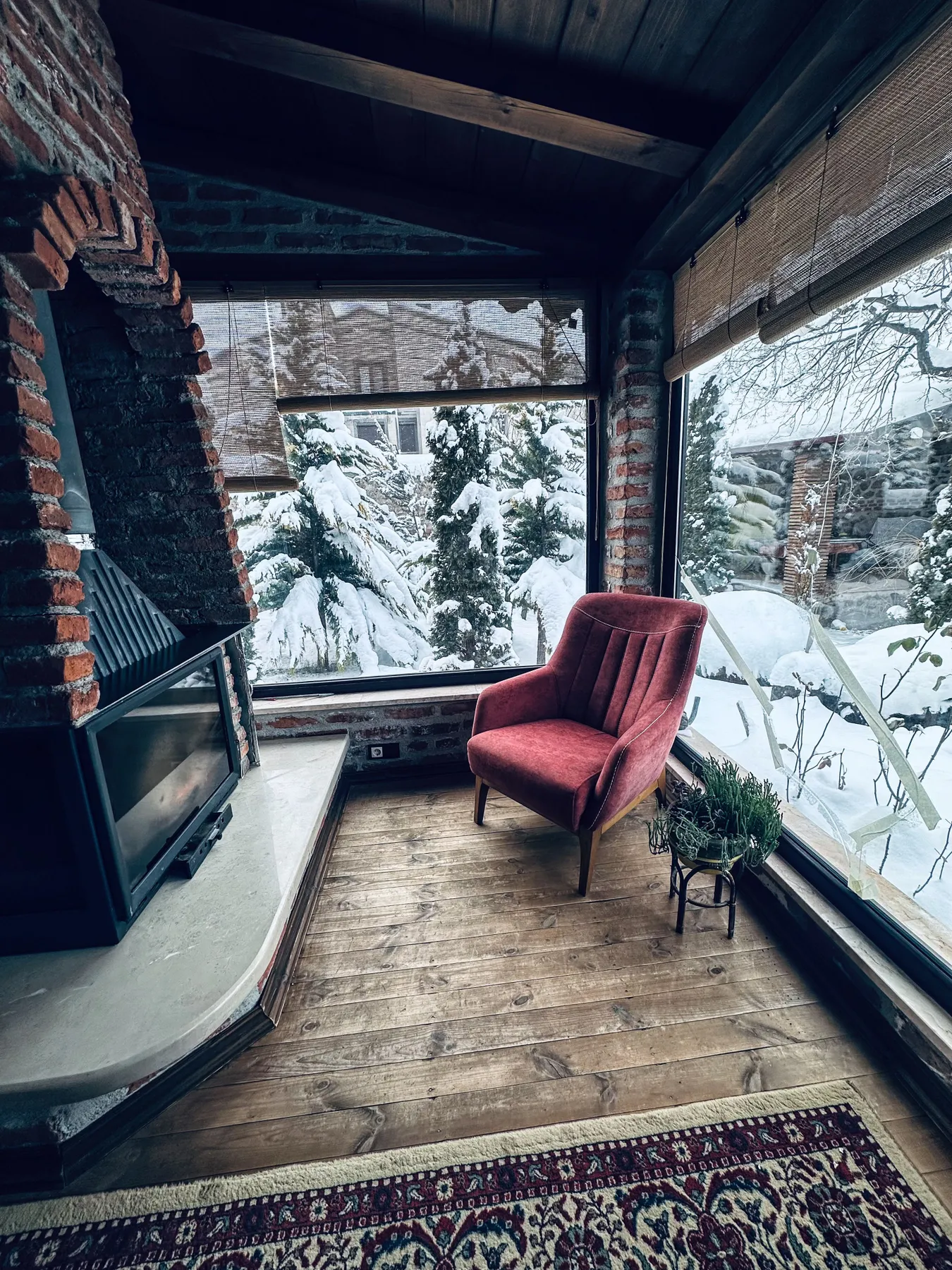 Warm interior featuring a fireplace and snowy outdoor view, perfect for winter relaxation.