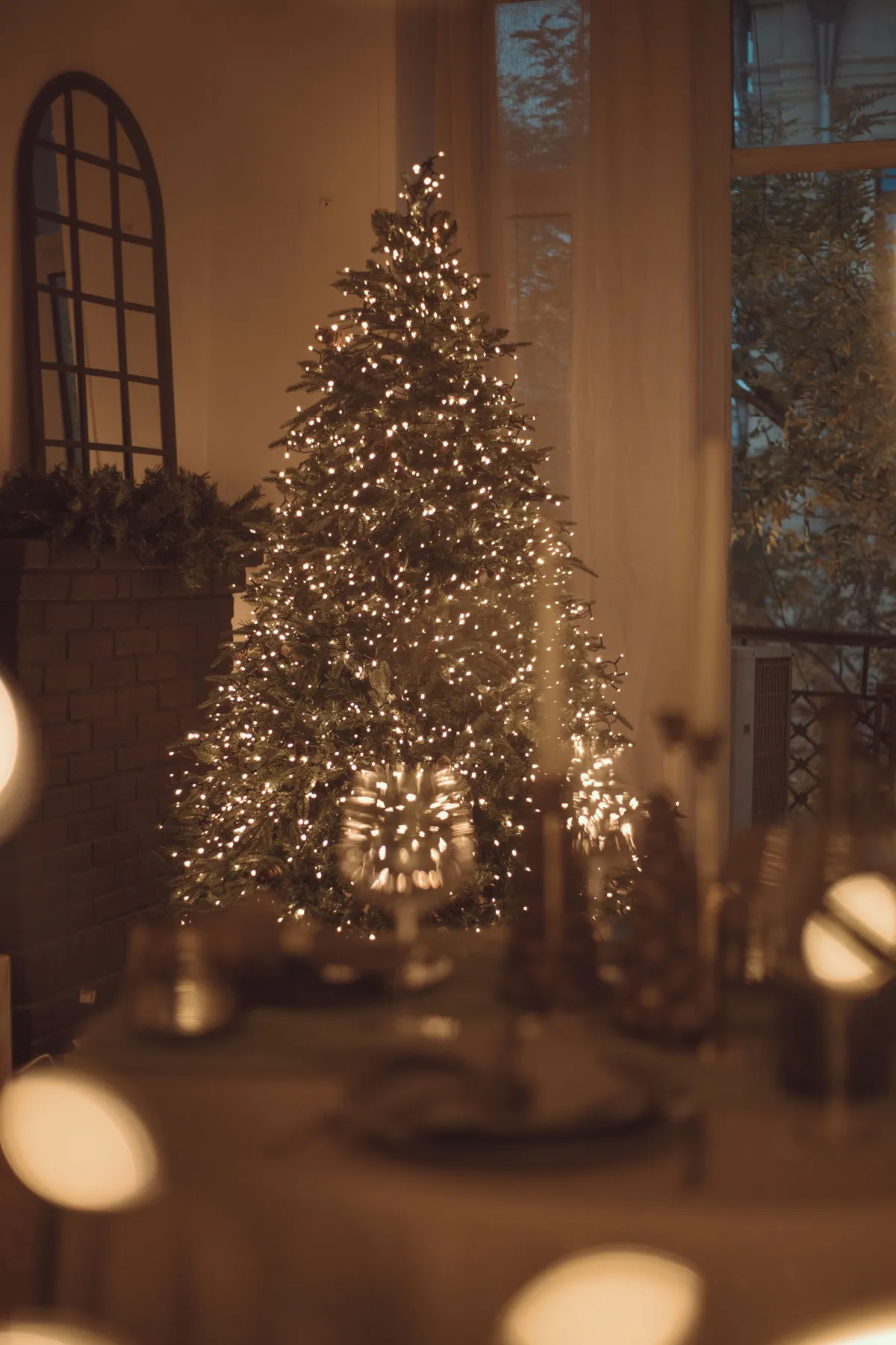 Warmly lit Christmas tree indoors adorned with lights, creating a cozy holiday atmosphere.